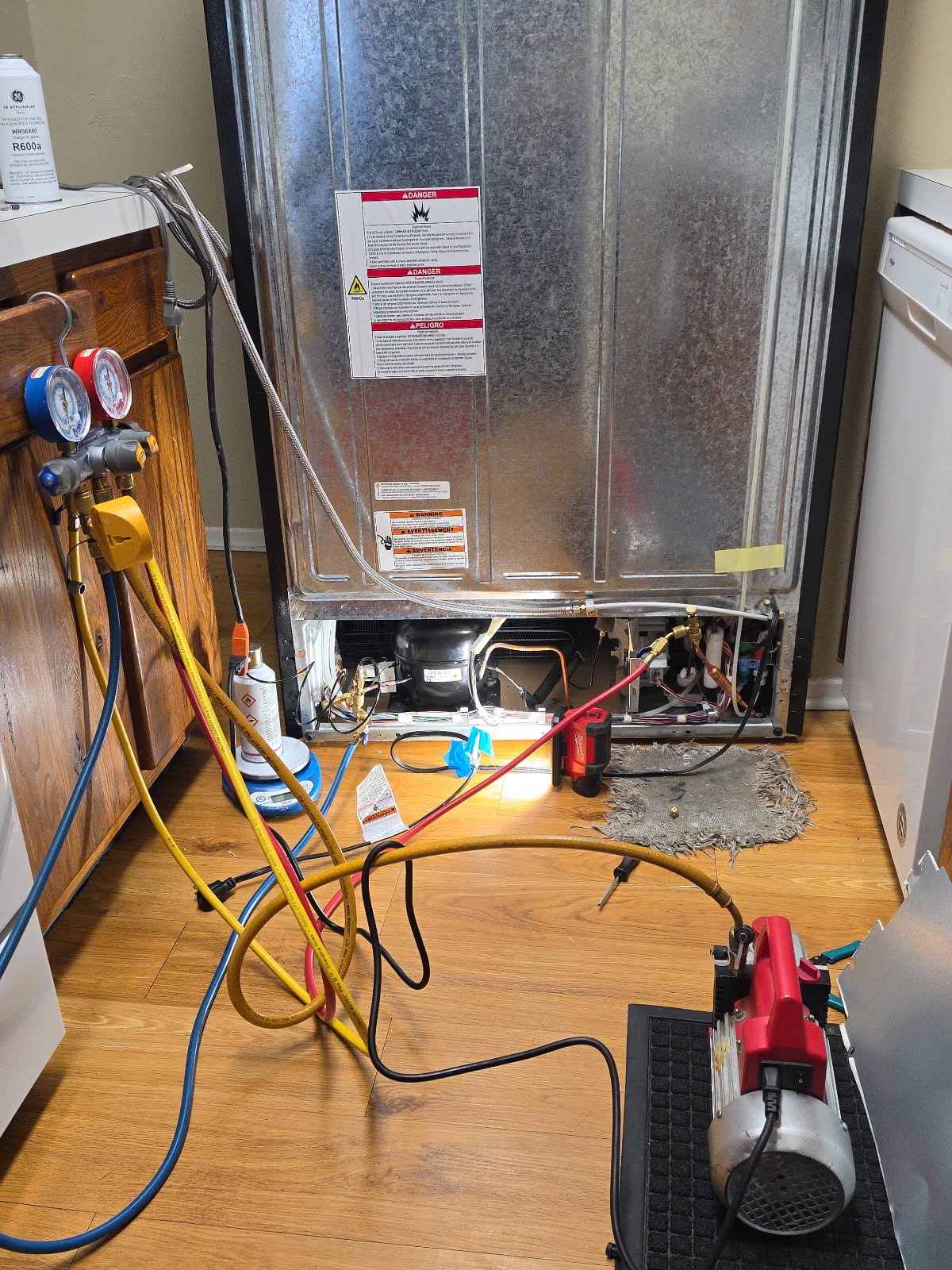 Refrigerator repair technician working on a refrigerator with diagnostic tools