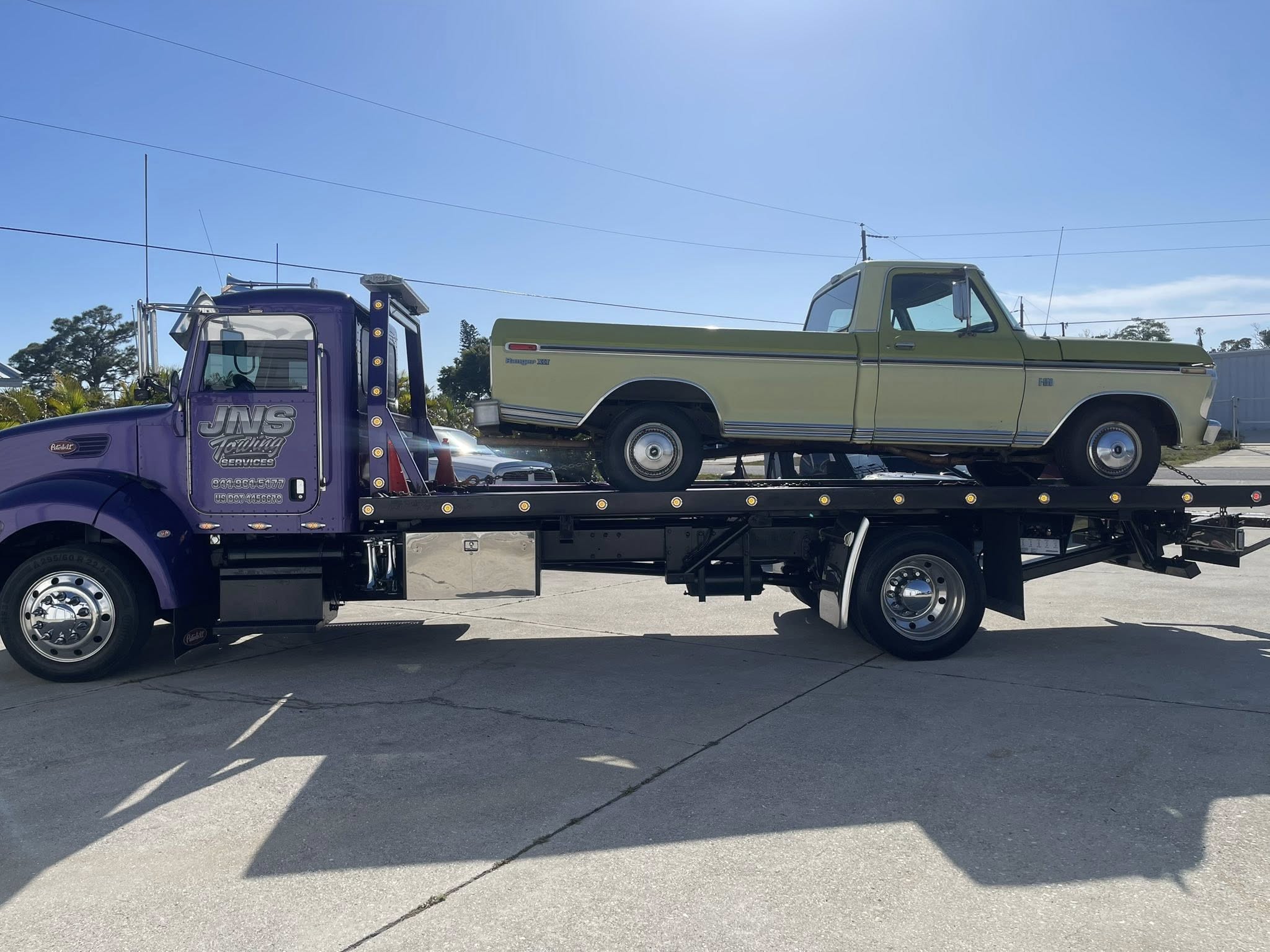 Flatbed towing a classic green pickup