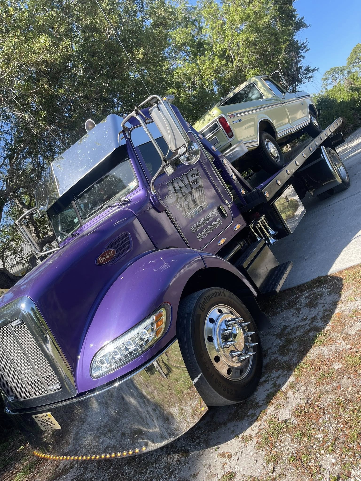 JNS Towing truck transporting a classic green truck