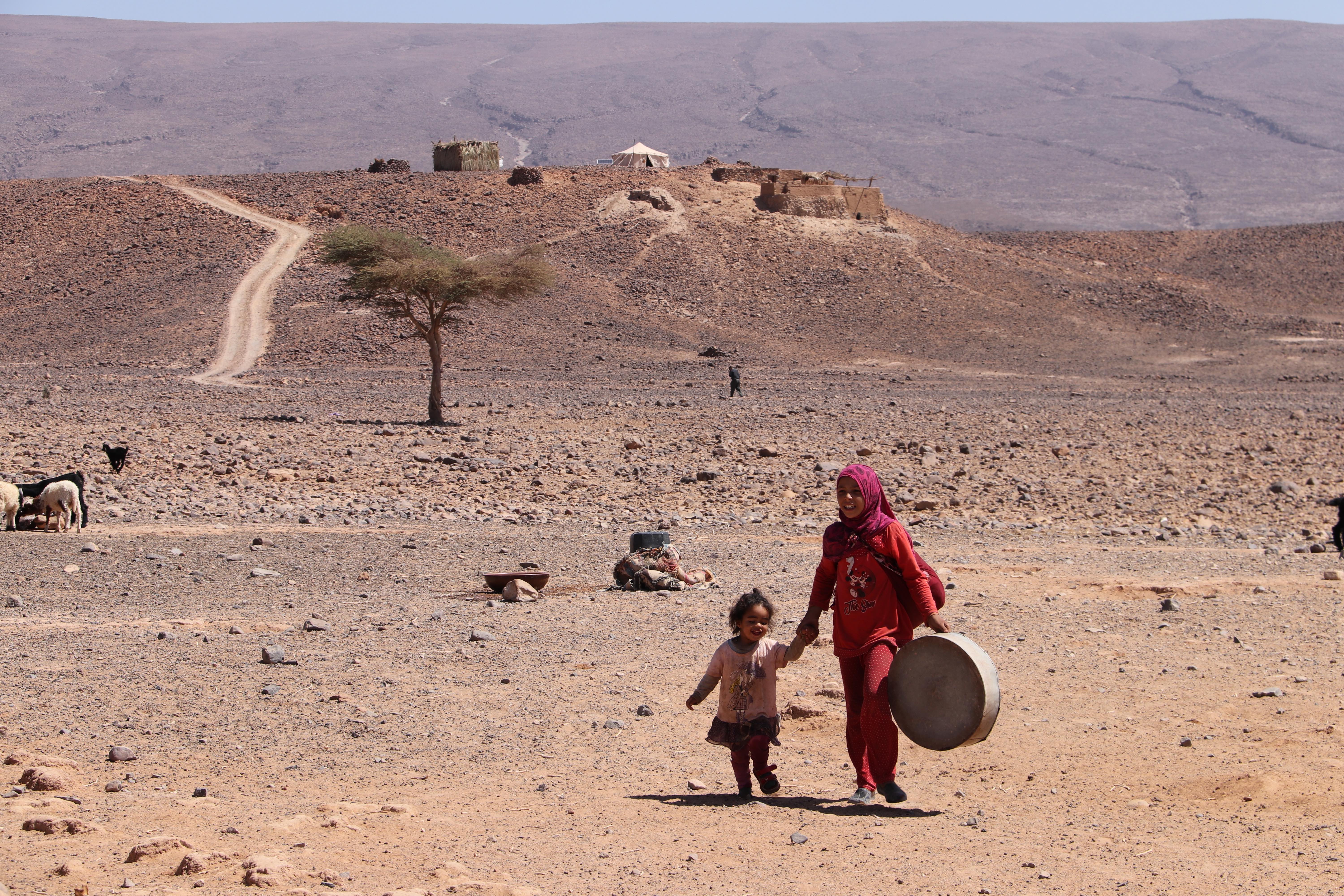 Morocco 2018 - Two Children Walking Across Desert Plateau with Drum