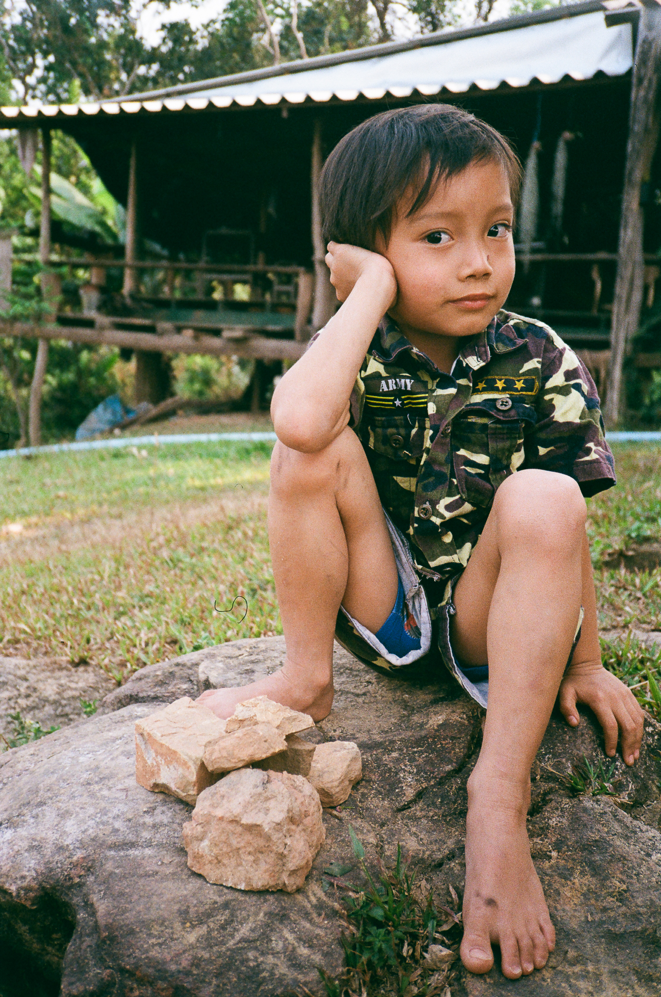 Golden moments in Thailand - Child Sitting on Rock in Camouflage Shirt