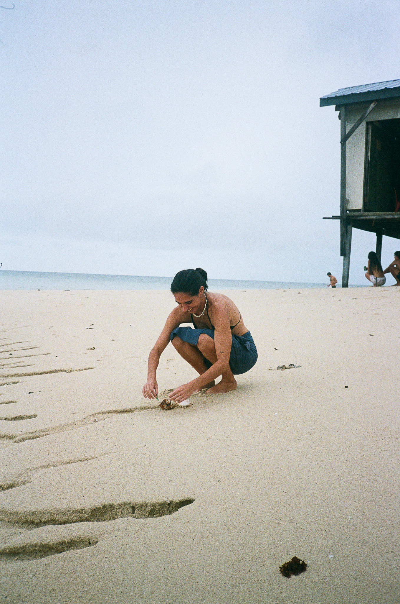 People of the Sea - Woman Crouching on Beach