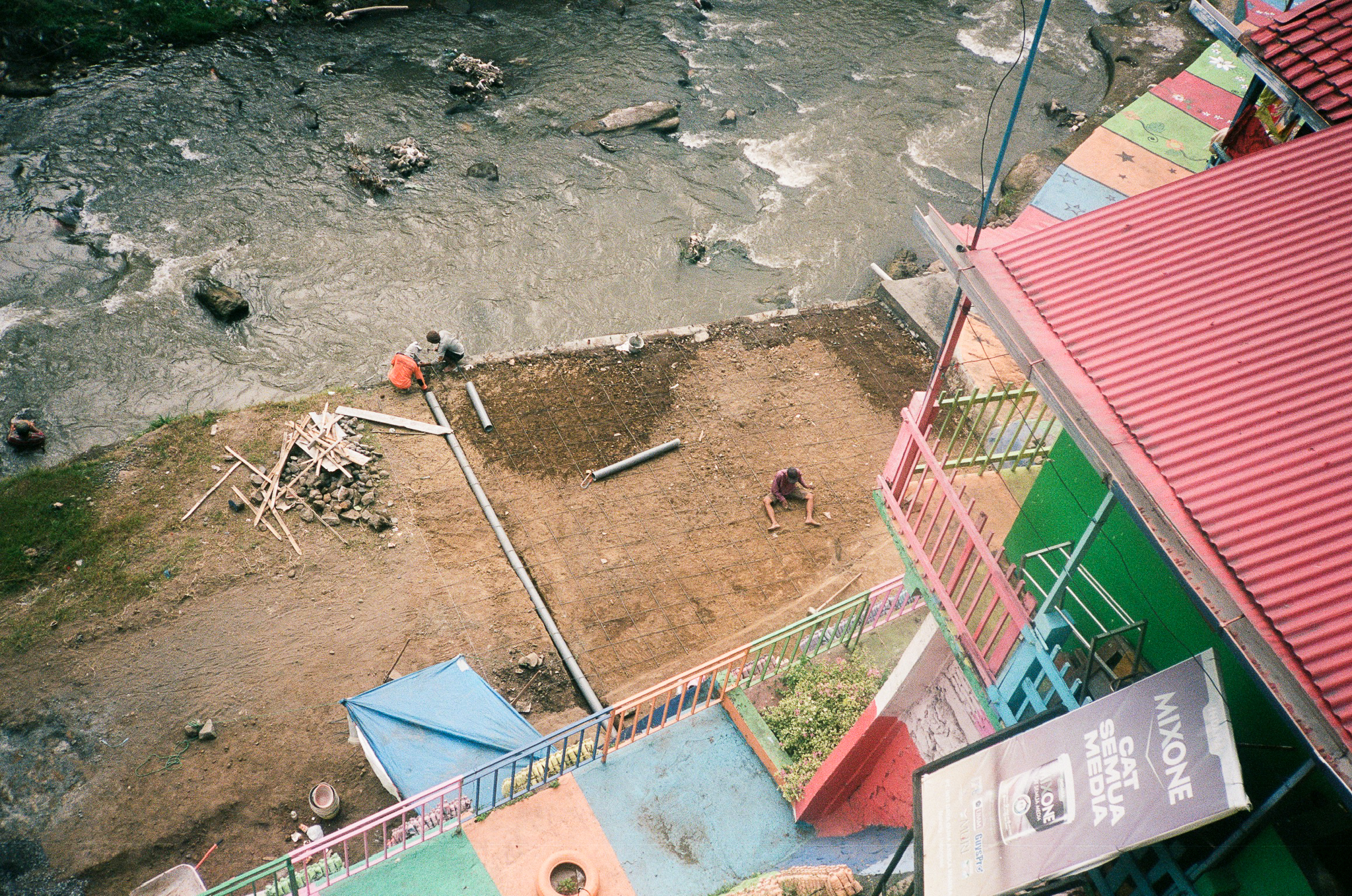 Echoes of Bromo - Riverbank Scene with Workers and Colorful Houses