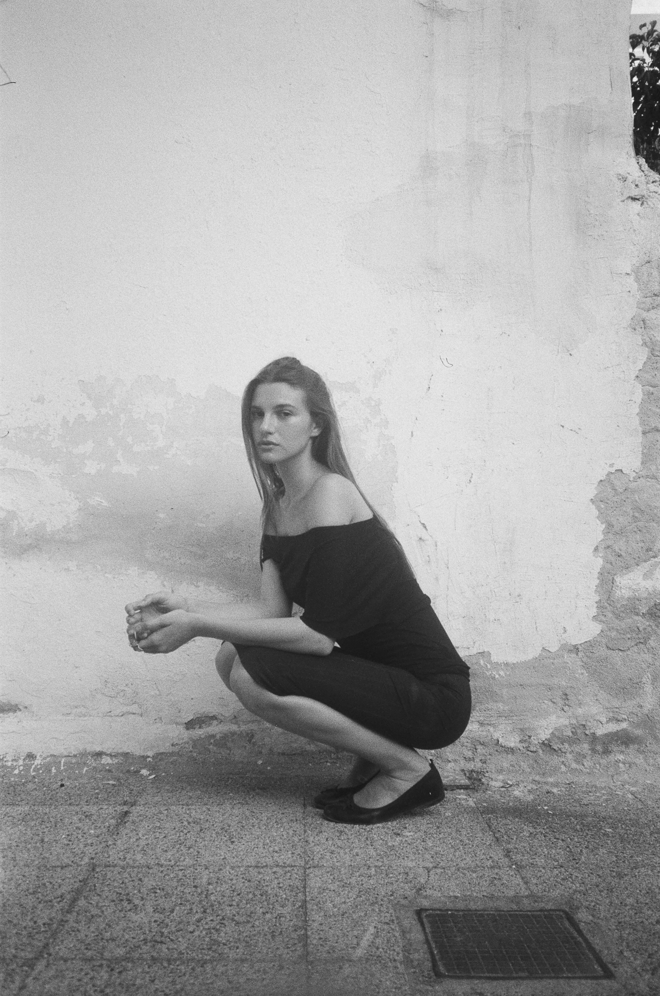 Stories of Greece - Crouching Portrait Against Wall B&W