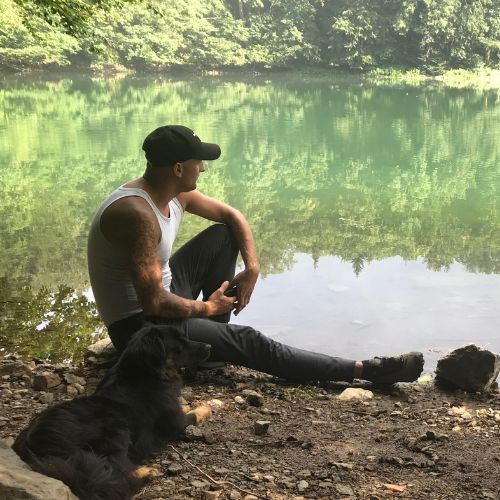 Michael Crijns, eigenaar Michael's Woodwork en Off-grid projecten specialist Maastricht Nederland zittend in de natuur met zijn hond