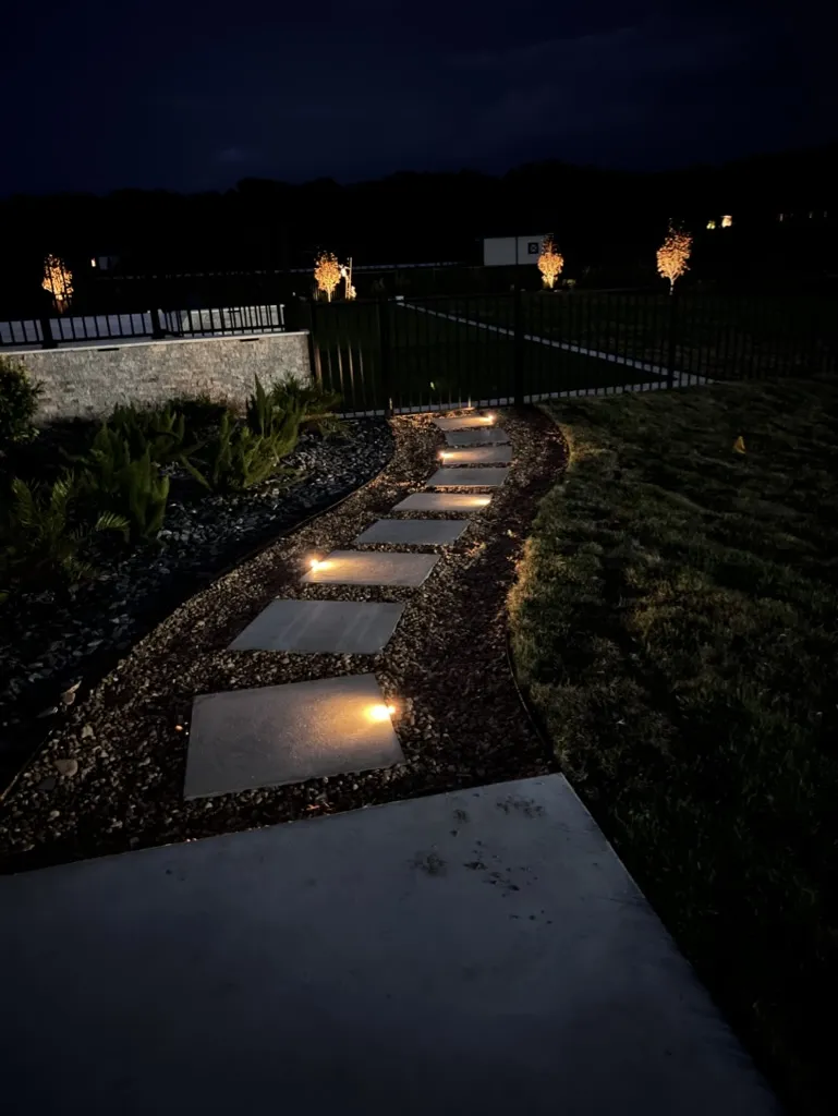 Illuminated stone path through a landscaped garden at night