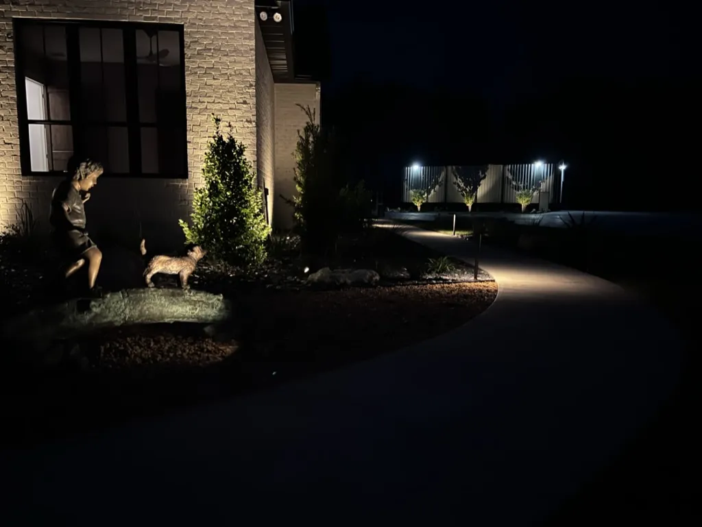 Outdoor landscape lighting highlighting a bronze statue and path