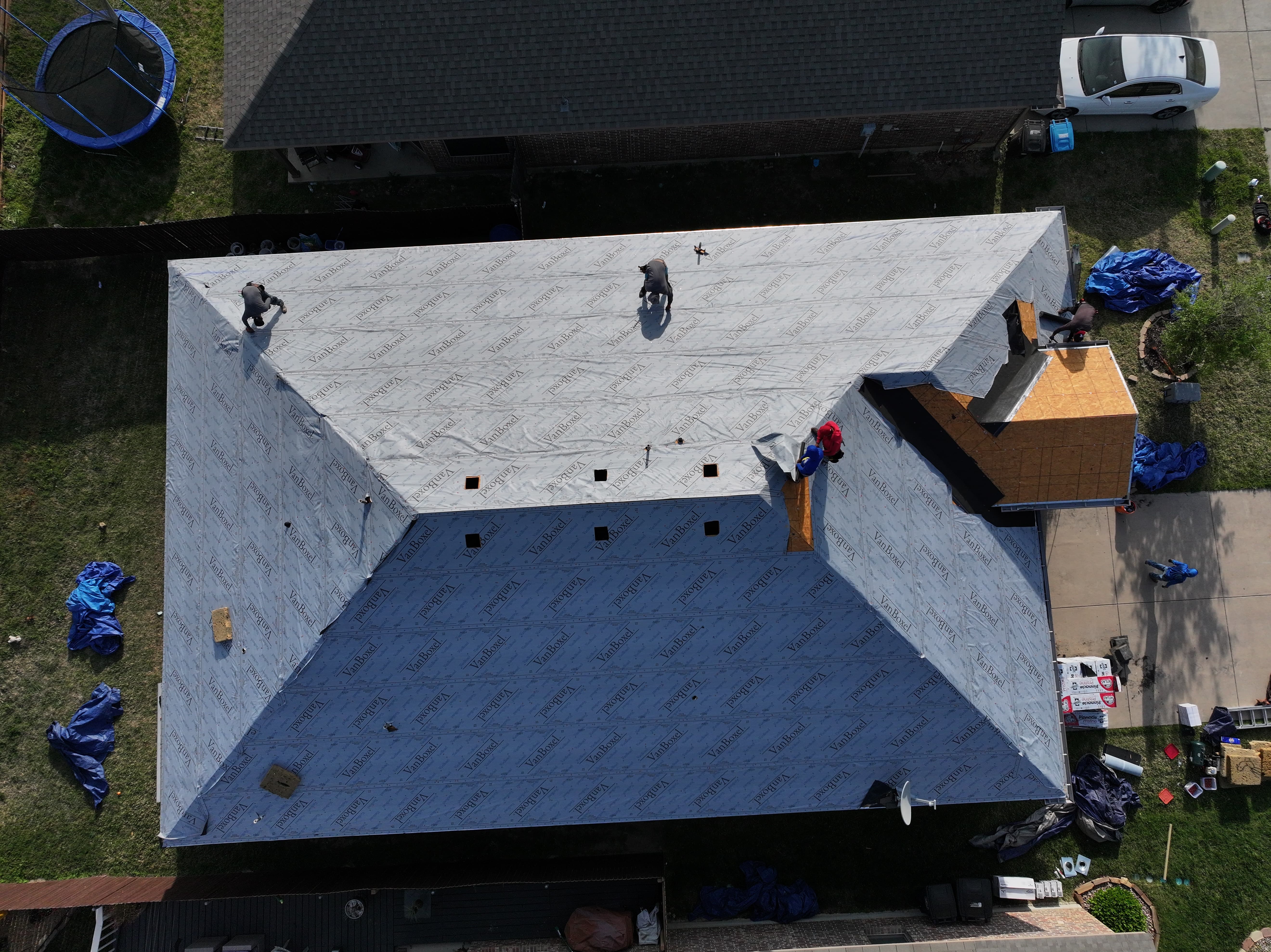 Roofing workers installing underlayment on roof