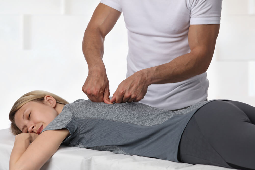 Osteopathic manual practitioner performing a gentle treatment on a patient's back to relieve pain and restore function.