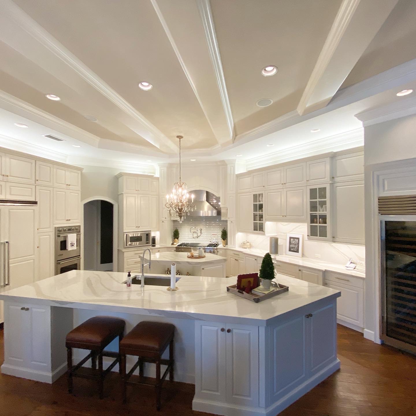 Modern kitchen with white cabinetry, elegant chandelier, and marble countertop, showcasing premium remodeling by Diamond Pro Finishes.