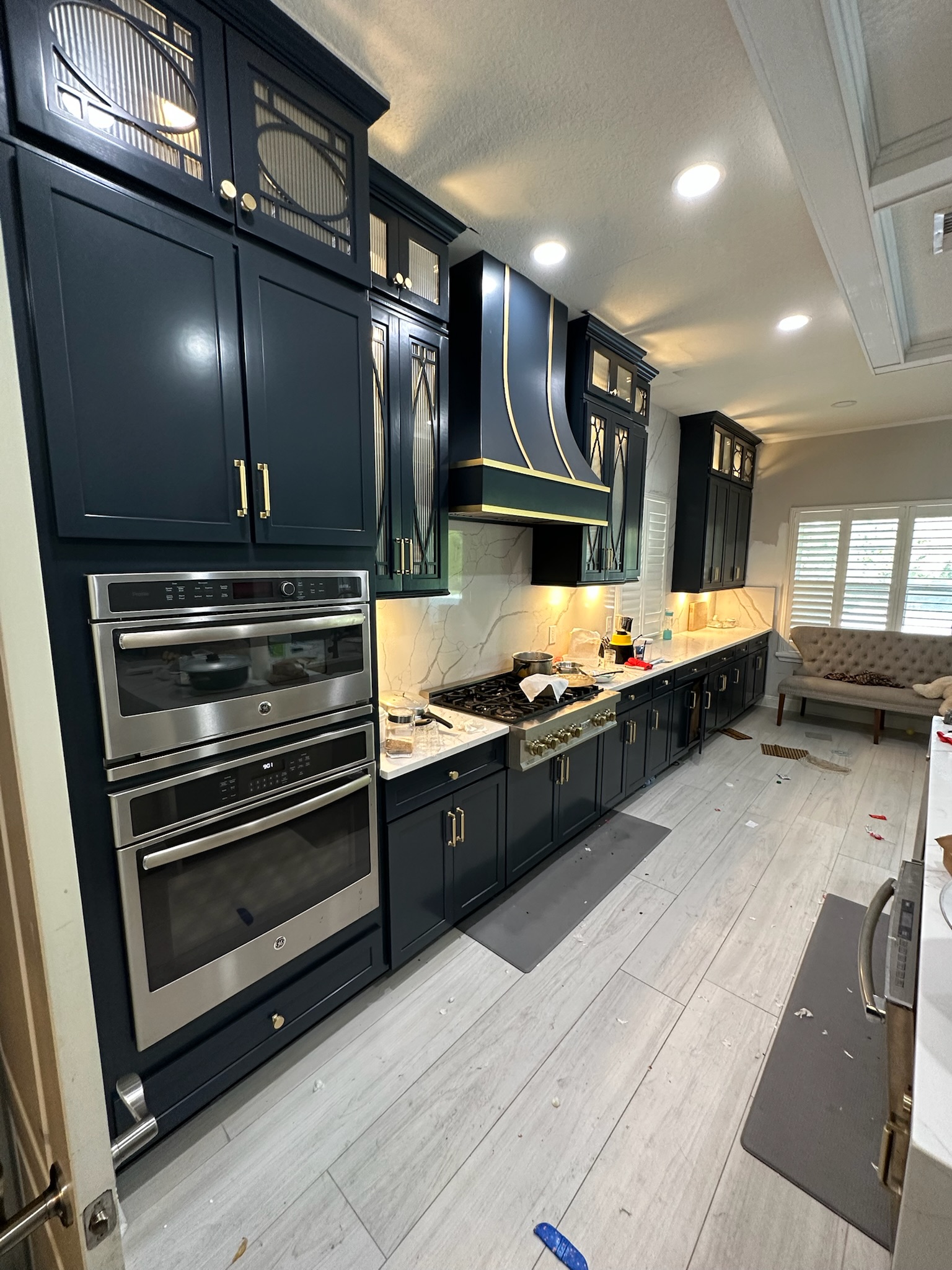 Modern kitchen featuring navy blue cabinetry with gold accents, stainless steel appliances, marble countertop, and a stylish range hood, emphasizing a remodel for functionality and aesthetics.