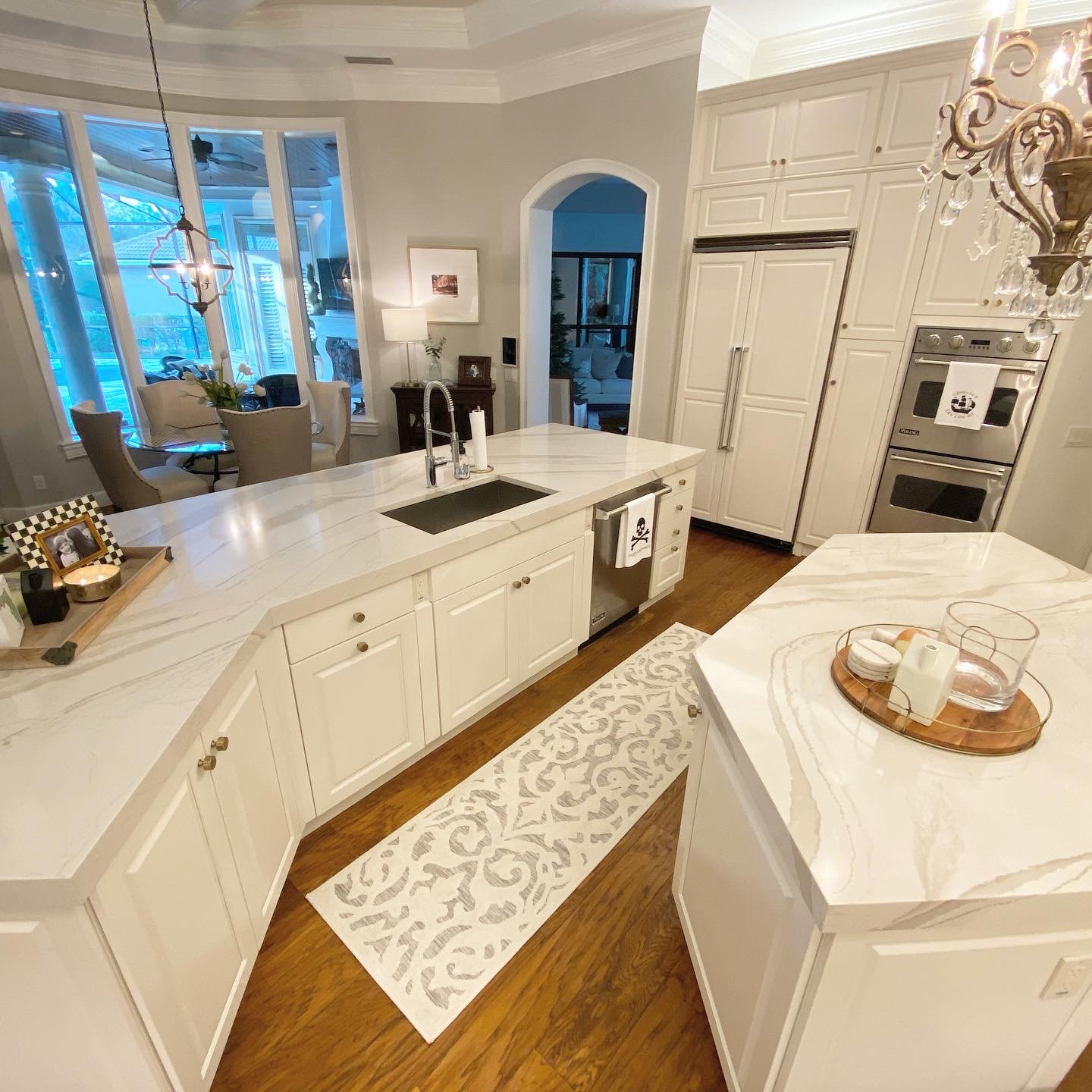 Modern kitchen featuring white cabinetry, elegant marble countertops, and a stylish rug, showcasing a sophisticated design ideal for home remodeling projects by Diamond Pro Finishes.