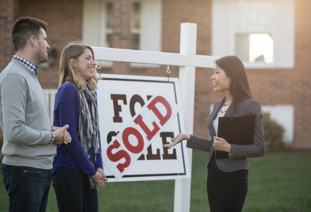Happy clients in front of sold home