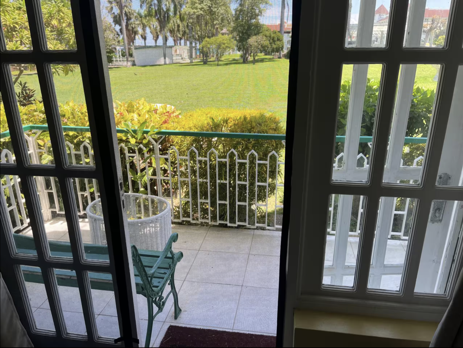 Open French Doors with Screen Leading to Private Tiled Patio Bench & Expansive Estate Lawns