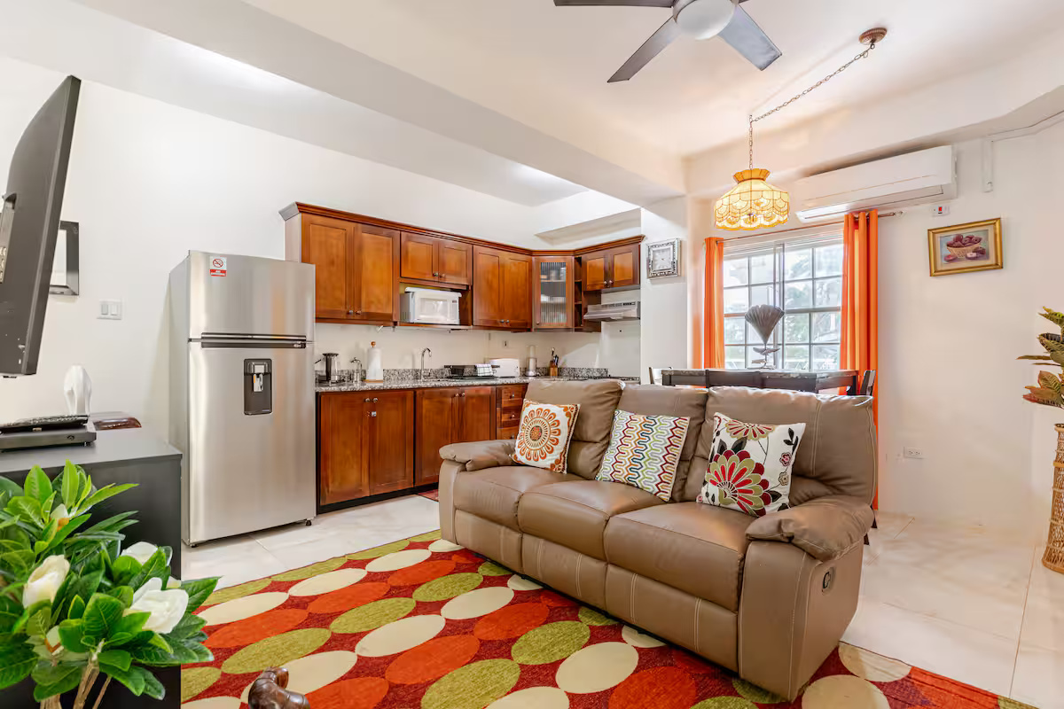 Living Salon with Leather Reclining Sofa, Colourful Accent Rug & Open Kitchen View