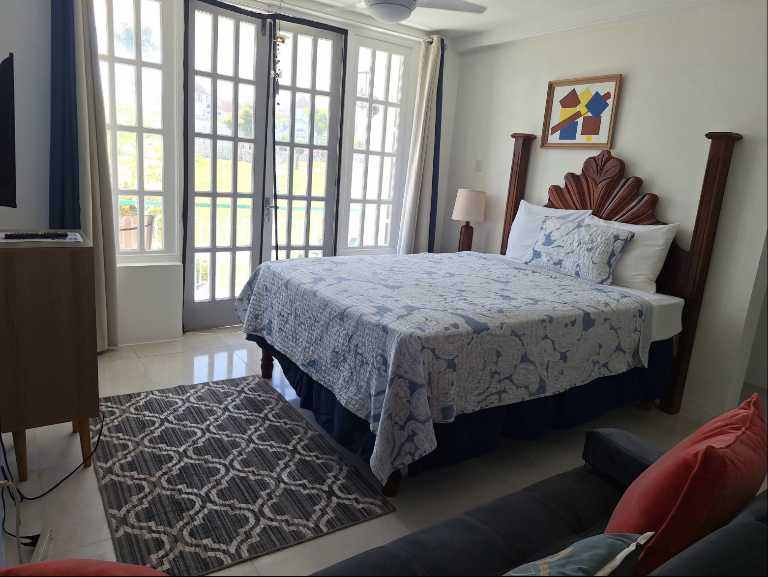 Sunlit Bedroom with French Balcony Doors, Sitting Area, TV & Geometric Accent Rug