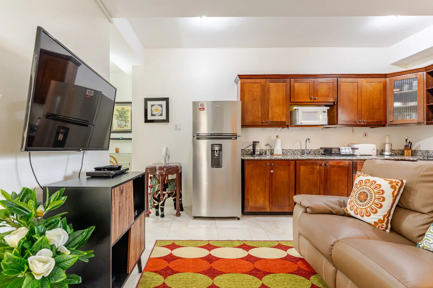 Open-Concept Kitchen & Living Area with Solid Wood Cabinets, Stainless Fridge & Smart TV