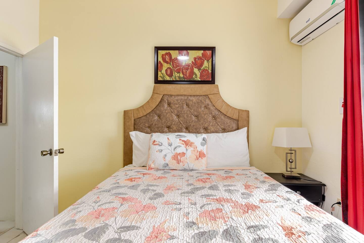 Cozy Second Bedroom with Plush Headboard, Floral Wall Art & Bedside Lamp