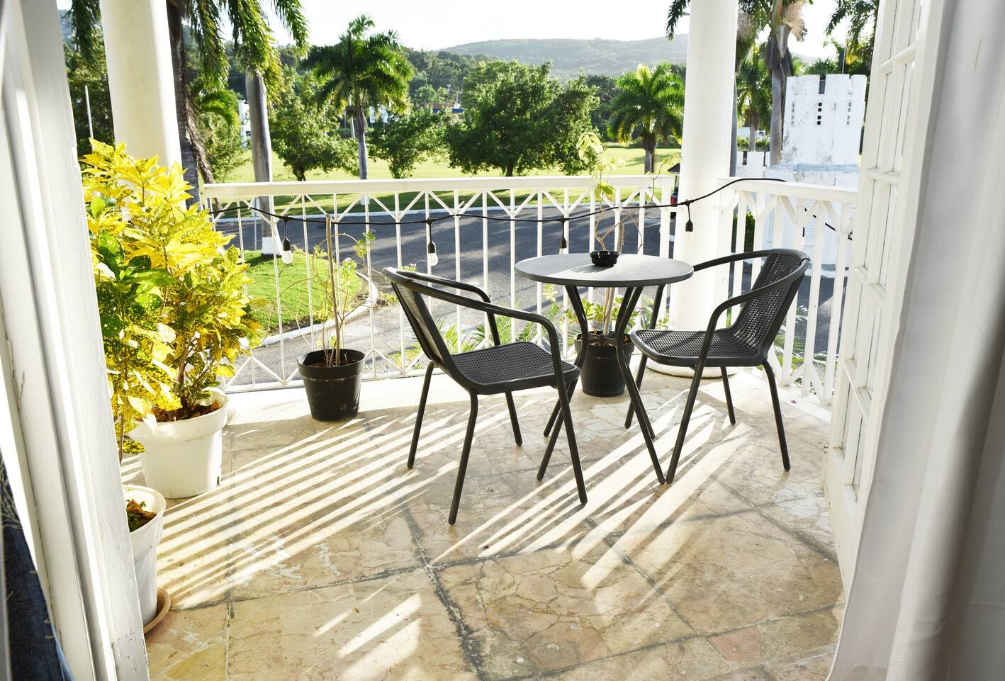 Sunlit Balcony Terrace with Bistro Table, Chairs & Lush Hillside Views