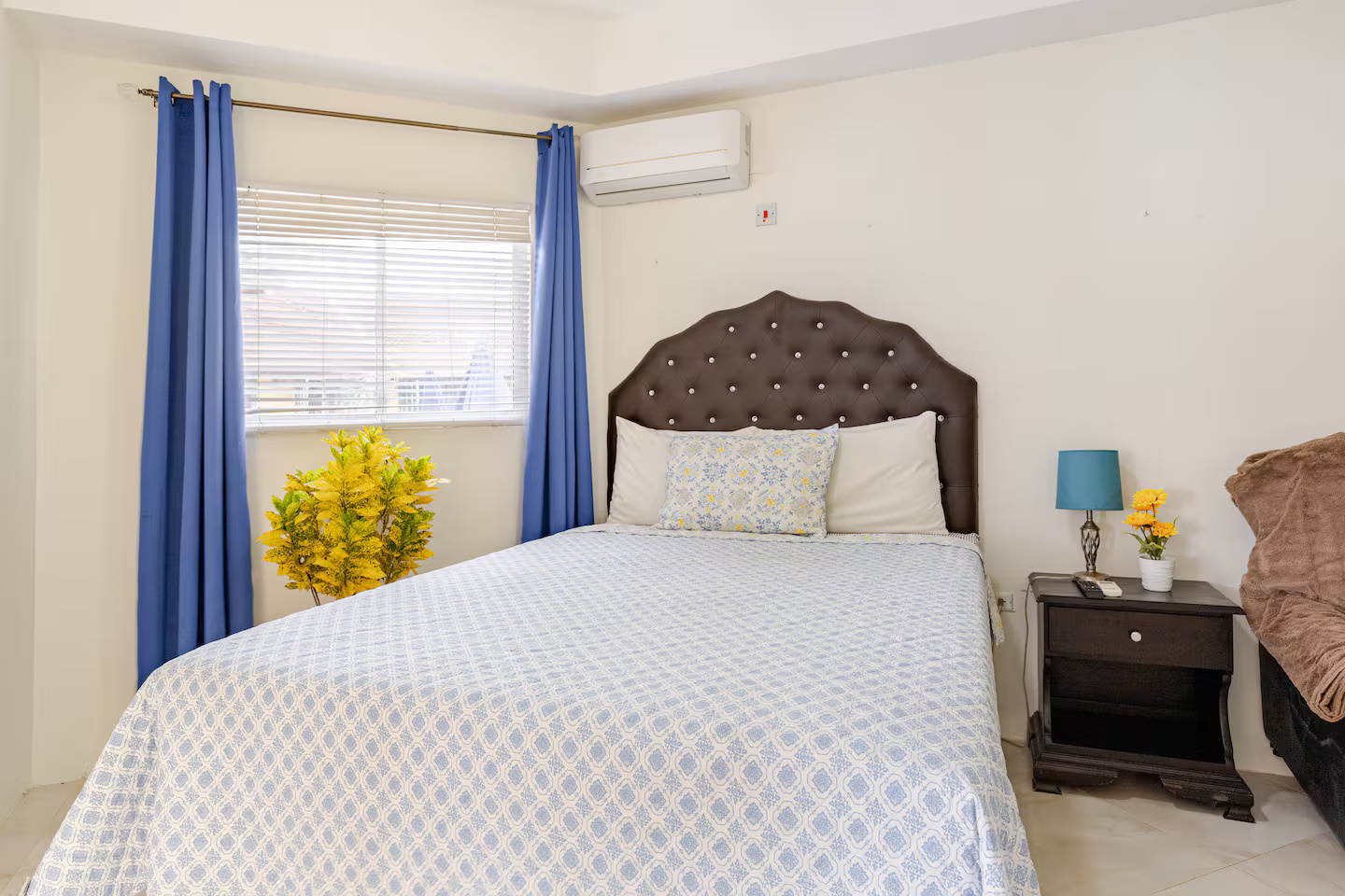 Inviting Bedroom with Tufted Dark Leather Headboard, Split A/C & Sunny Tropical Window