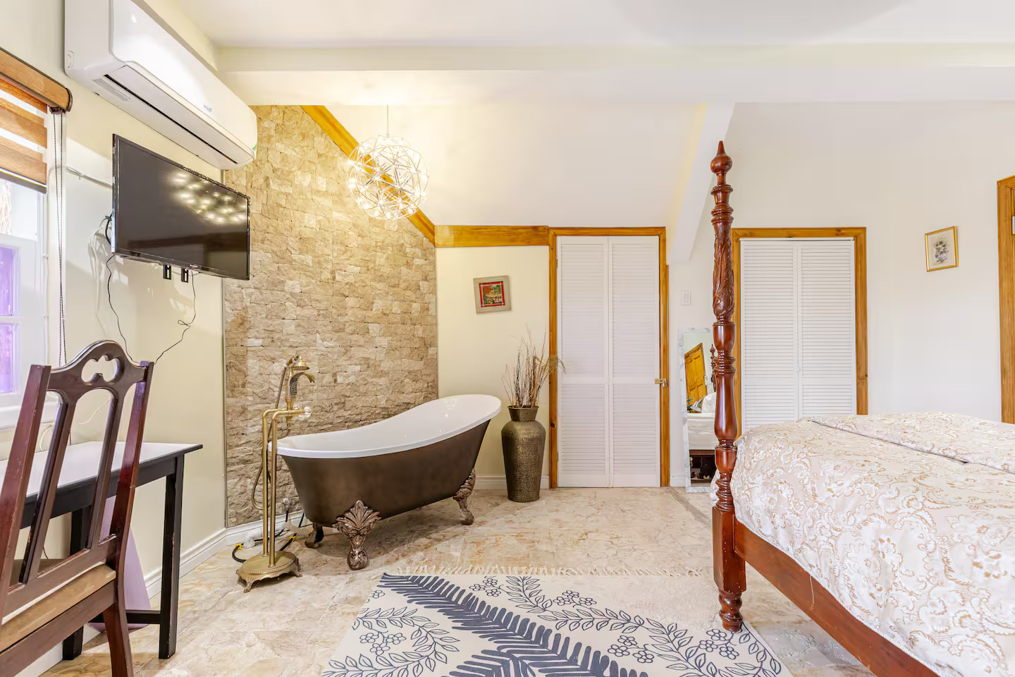 Freestanding Soaker Tub Against Natural Stone Wall with Modern Chandelier