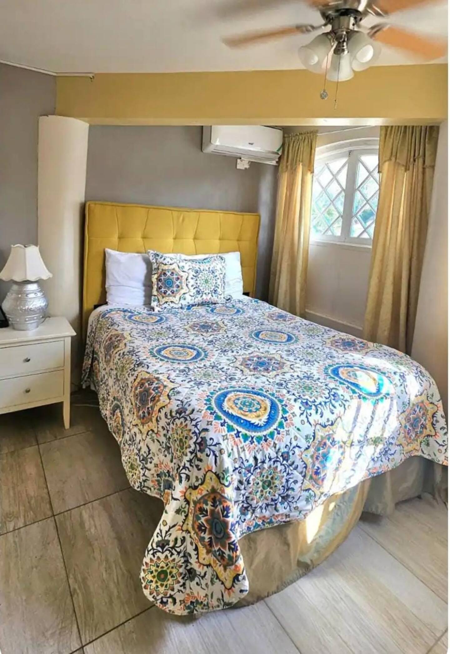 Sunlit Master Bedroom with Mustard Tufted Headboard & Tropical Bedspread