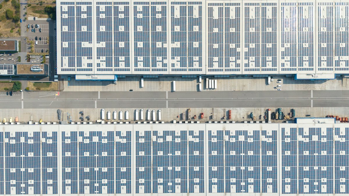 Aerial view of large warehouse roofs covered with solar panels, with loading docks