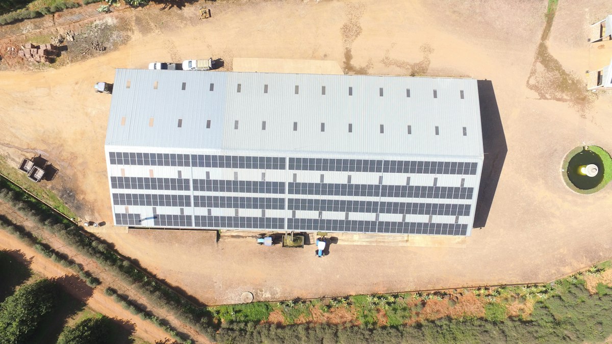 Building with solar panels, surrounded by dirt and trees