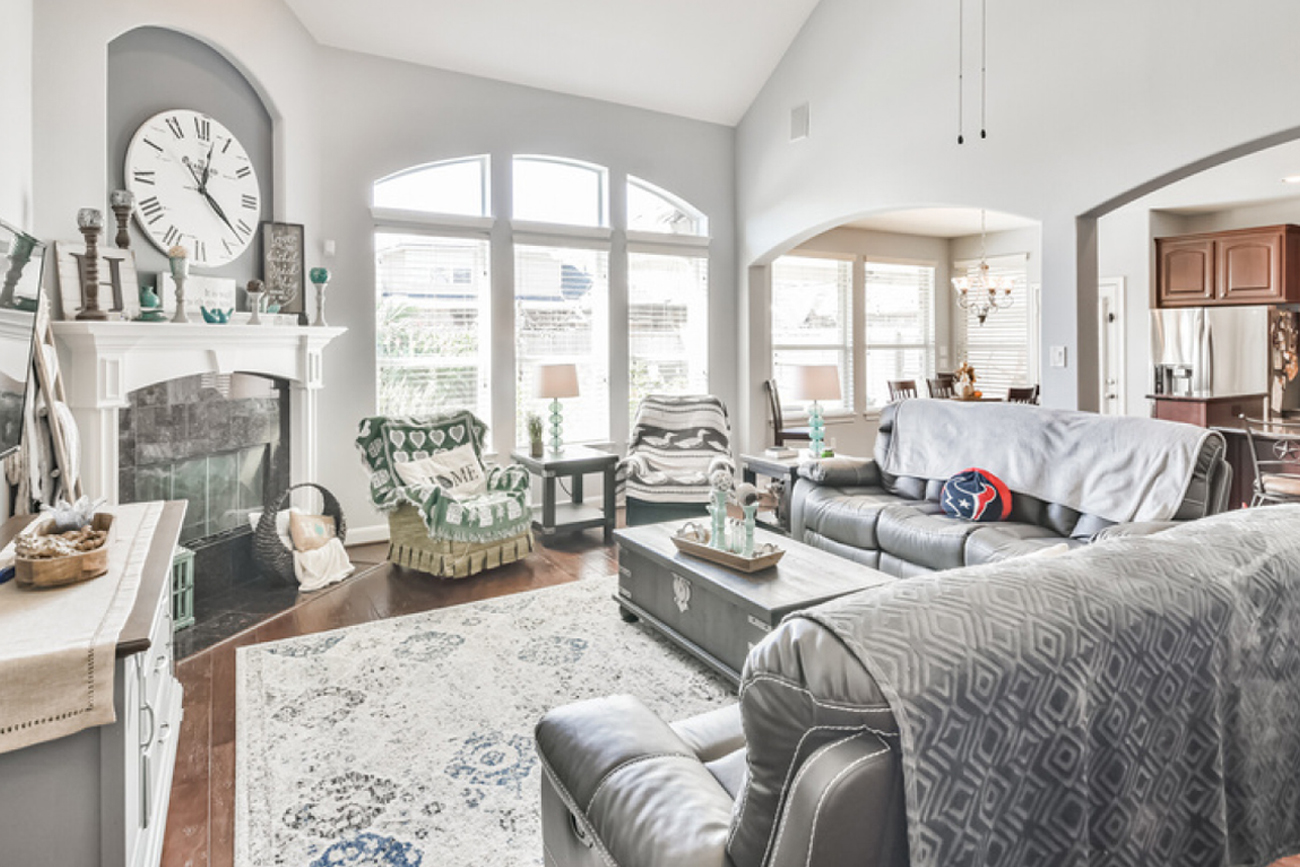 Spacious living room featuring a cozy fireplace, decorative clock, comfortable seating, and large windows allowing natural light, ideal for showcasing rural residential properties in Texas.