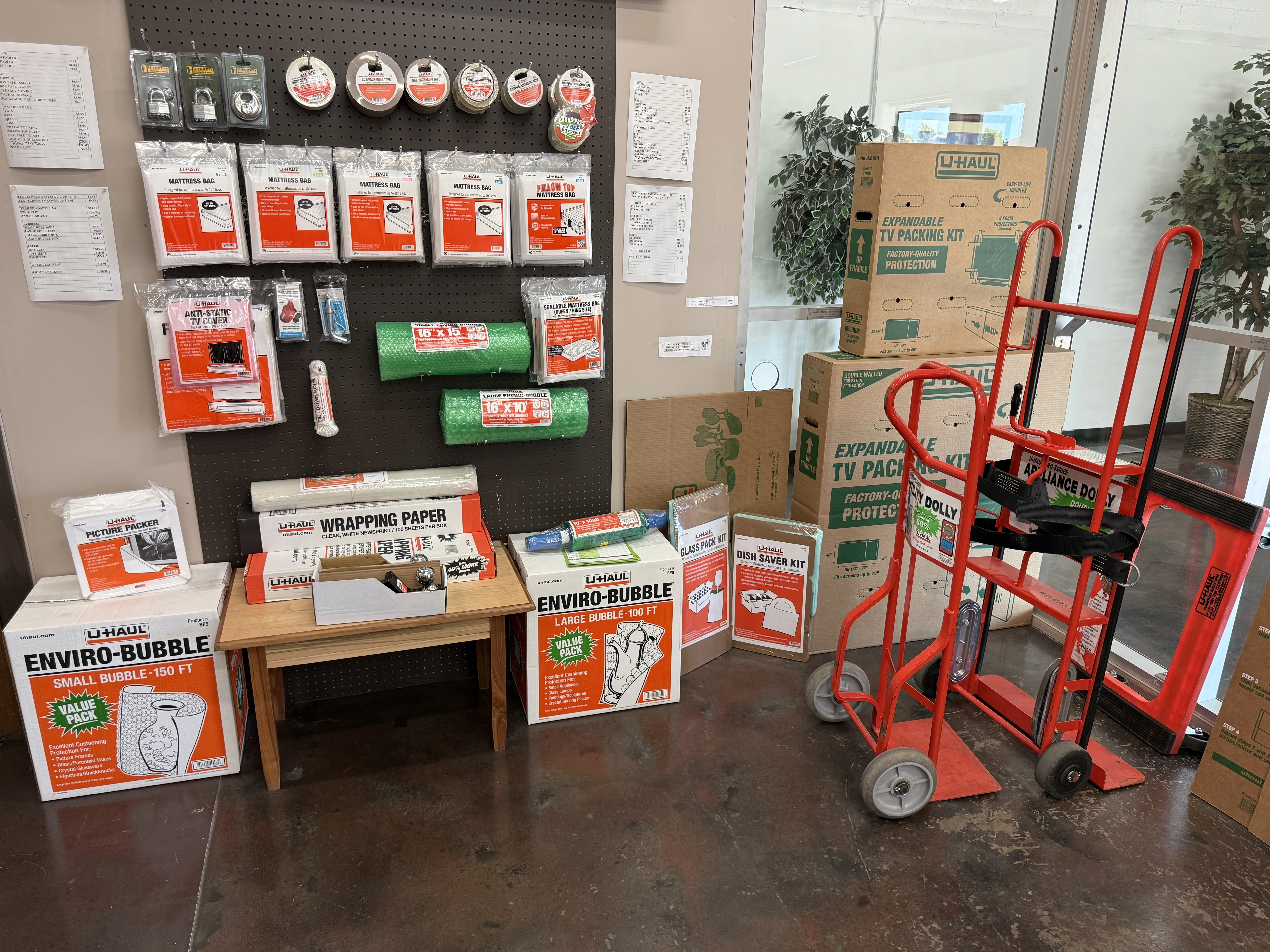 U-Haul moving supplies display at Sunbrook Secure Storage in St. George, Utah showing boxes, bubble wrap, packing tape, mattress bags, furniture covers, hand trucks, and TV moving kits available for purchase
