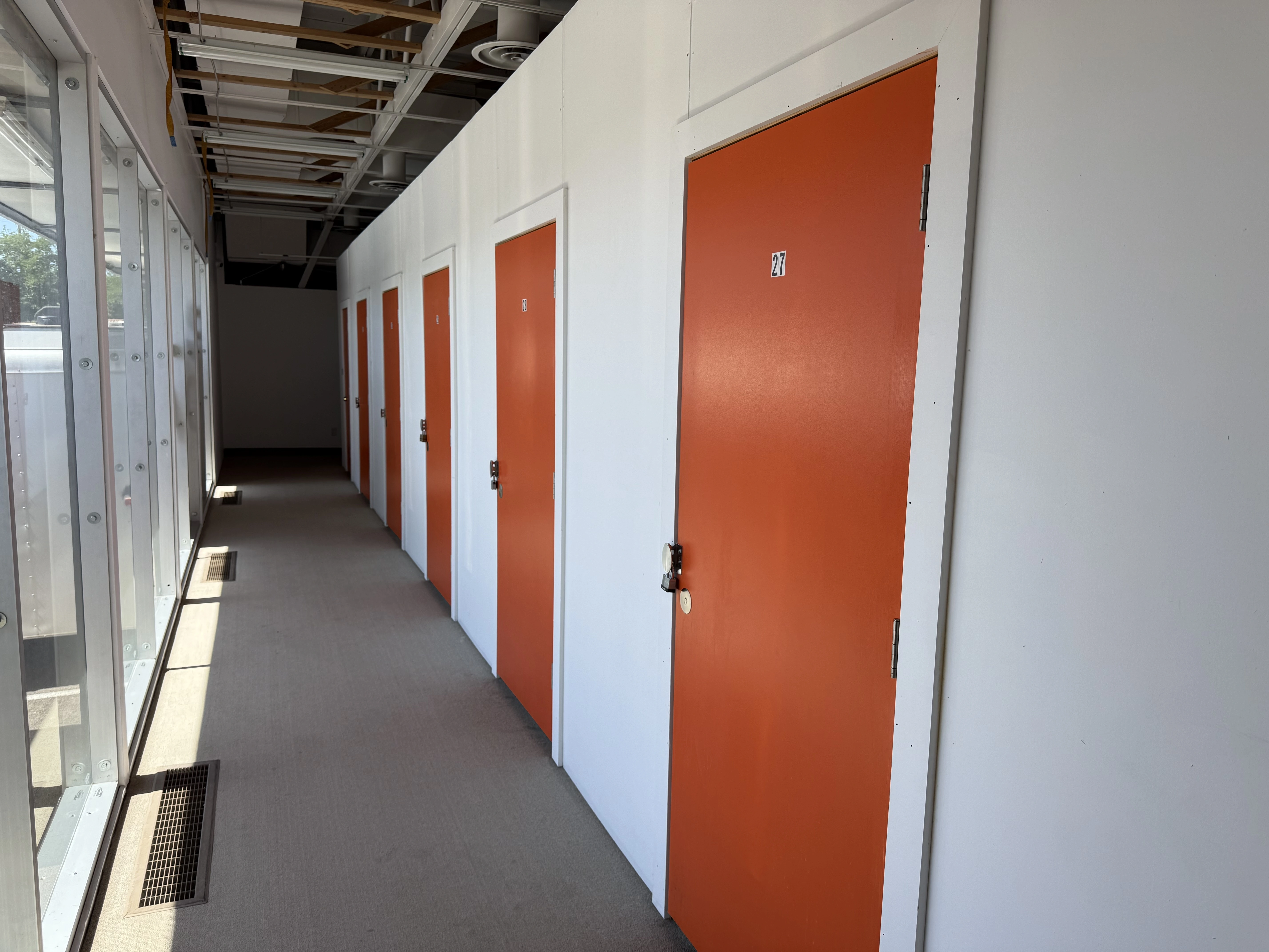 Indoor air-cooled student storage units at Sunbrook Secure Storage in St. George, Utah showing orange roll-up doors and clean facility hallway