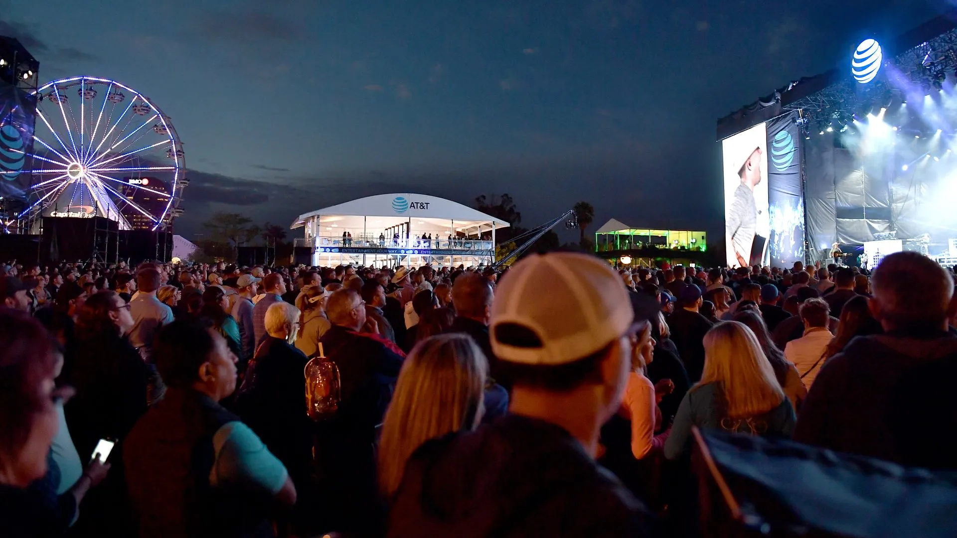 Large festival crowd with ferris wheel and stage lights — comedy hypnosis show entertainment for fairs and festivals