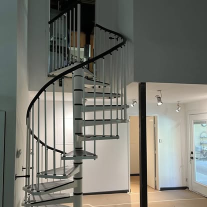 Spiral Staircase Installation - Spiral staircase install — gray metal spiral stair with black handrail in open-plan space