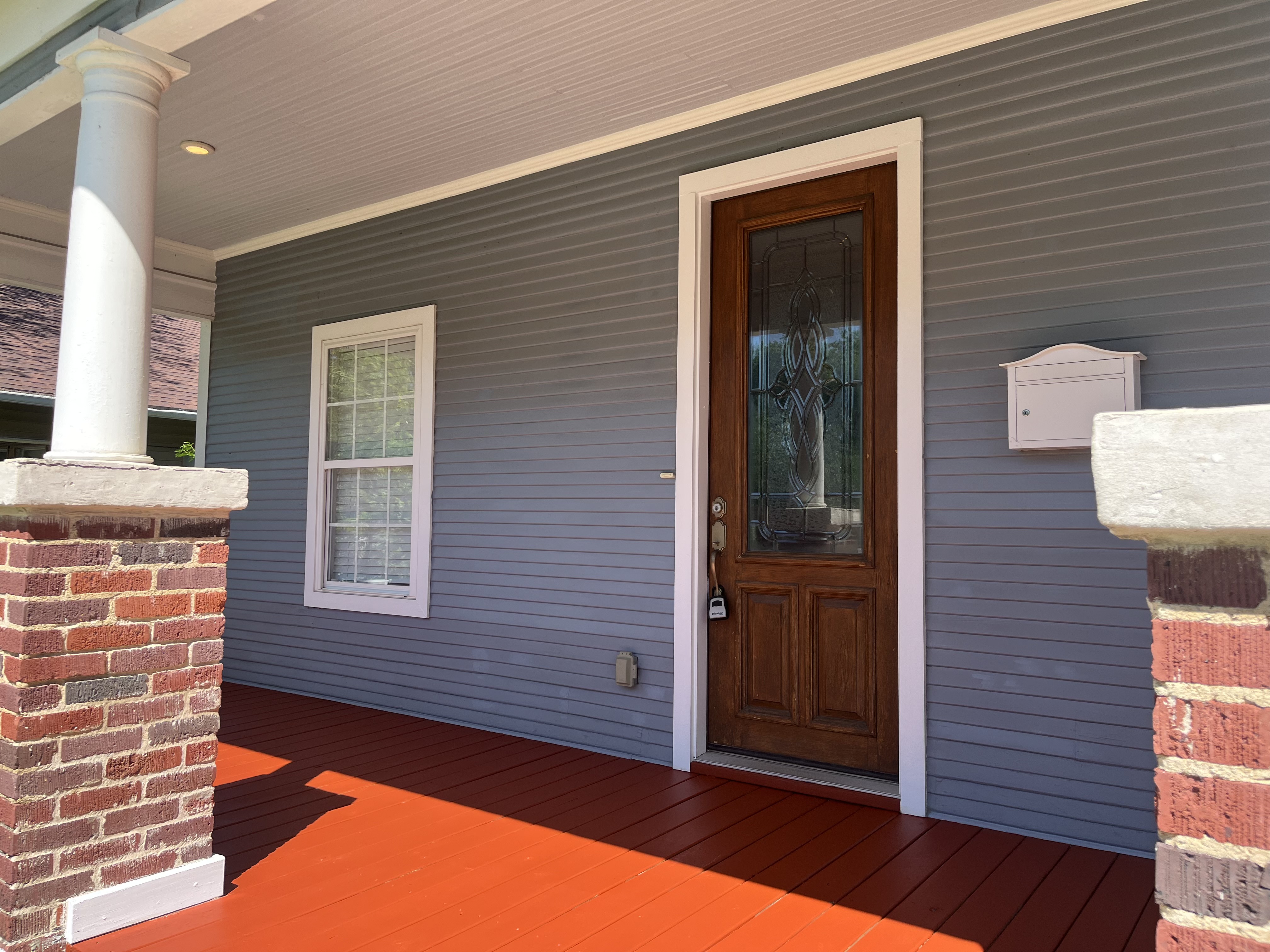Close-up of front entry door area showing porch detail, mailbox mount, and siding