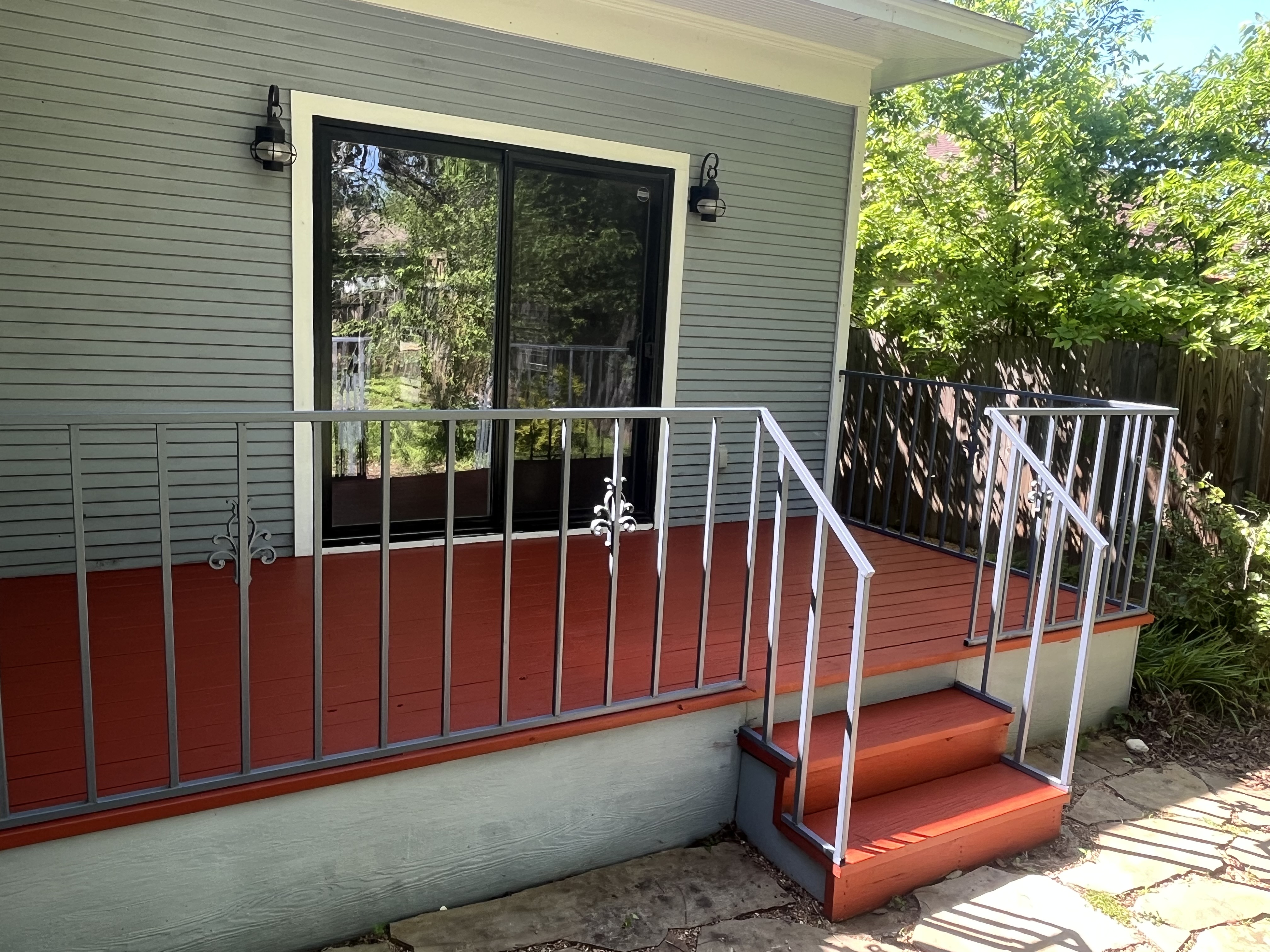 Back/side deck with painted red deck boards, metal railing system with decorative scroll accents - Angle 1