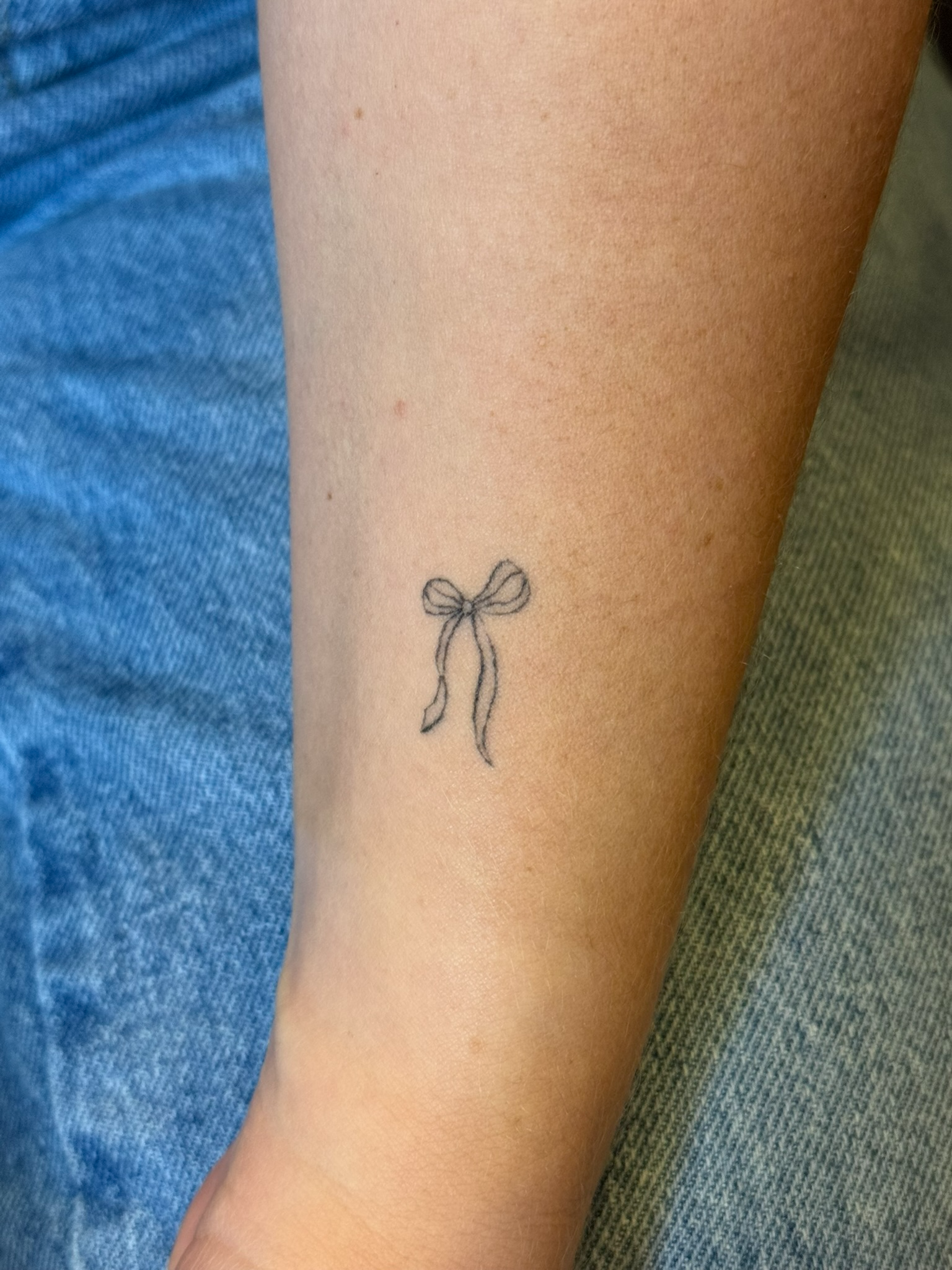 Healed delicate fine line bow tattoo