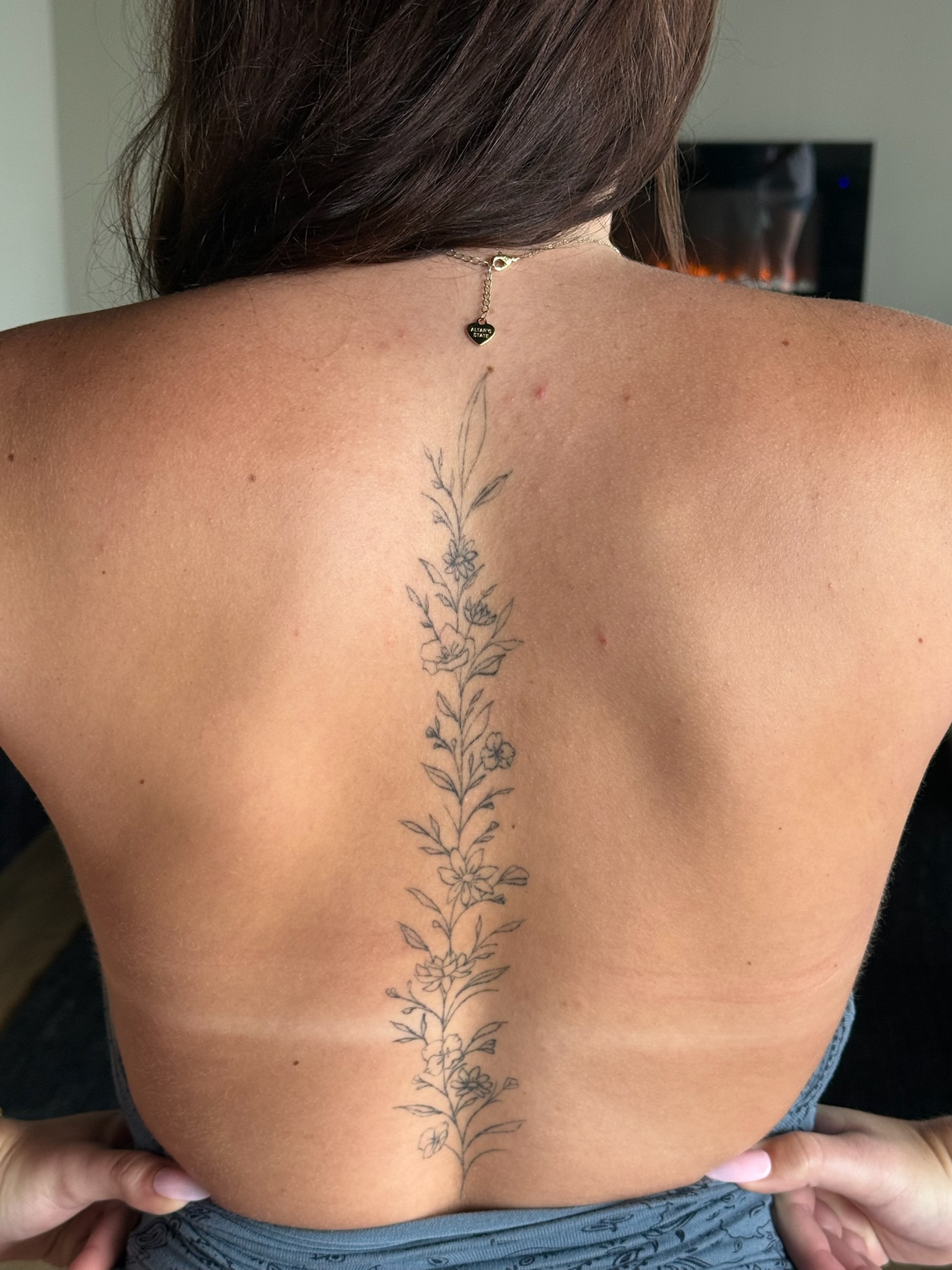 Healed fine line botanical spine tattoo along client's back