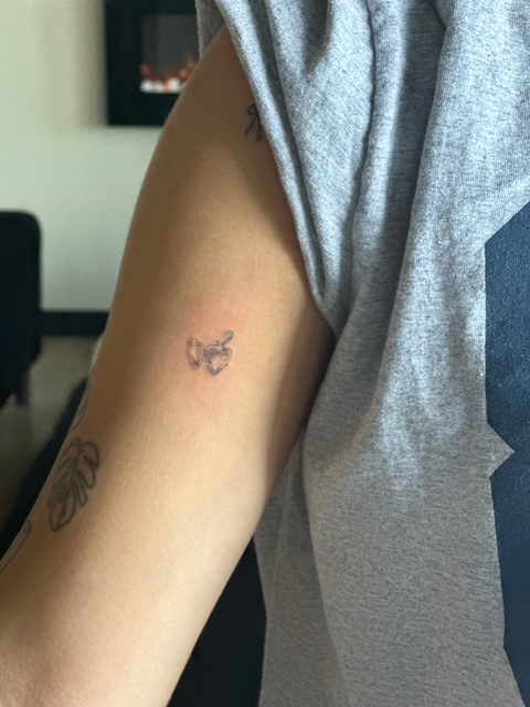 Healed fine line locket tattoo on client's upper arm