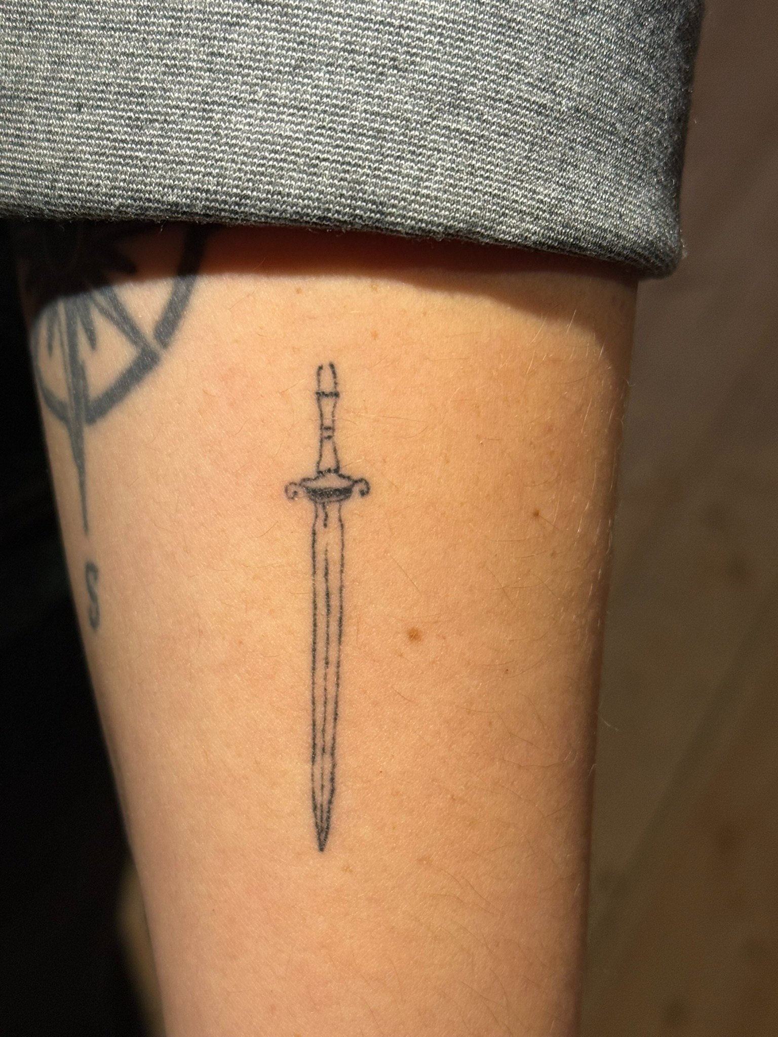 Healed fine line sword tattoo