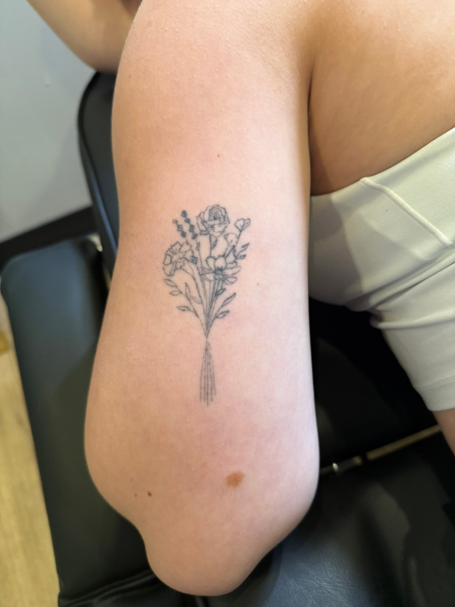 Healed delicate floral bouquet fine line tattoo on bicep