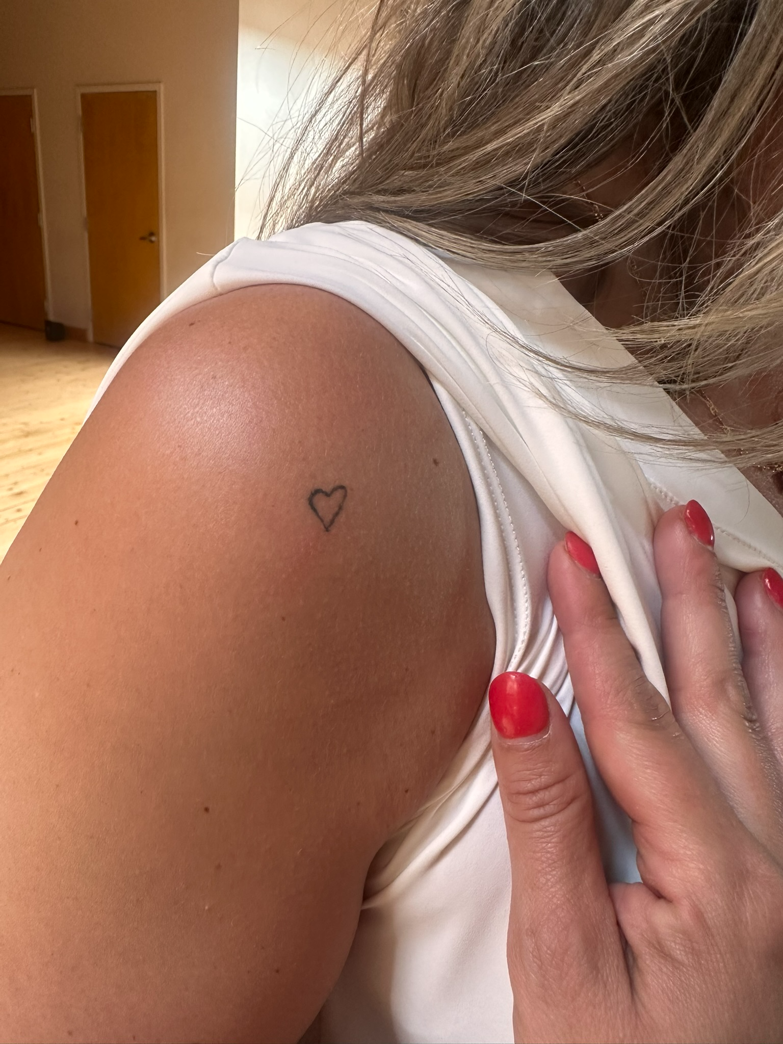 Healed fine line heart tattoo on shoulder
