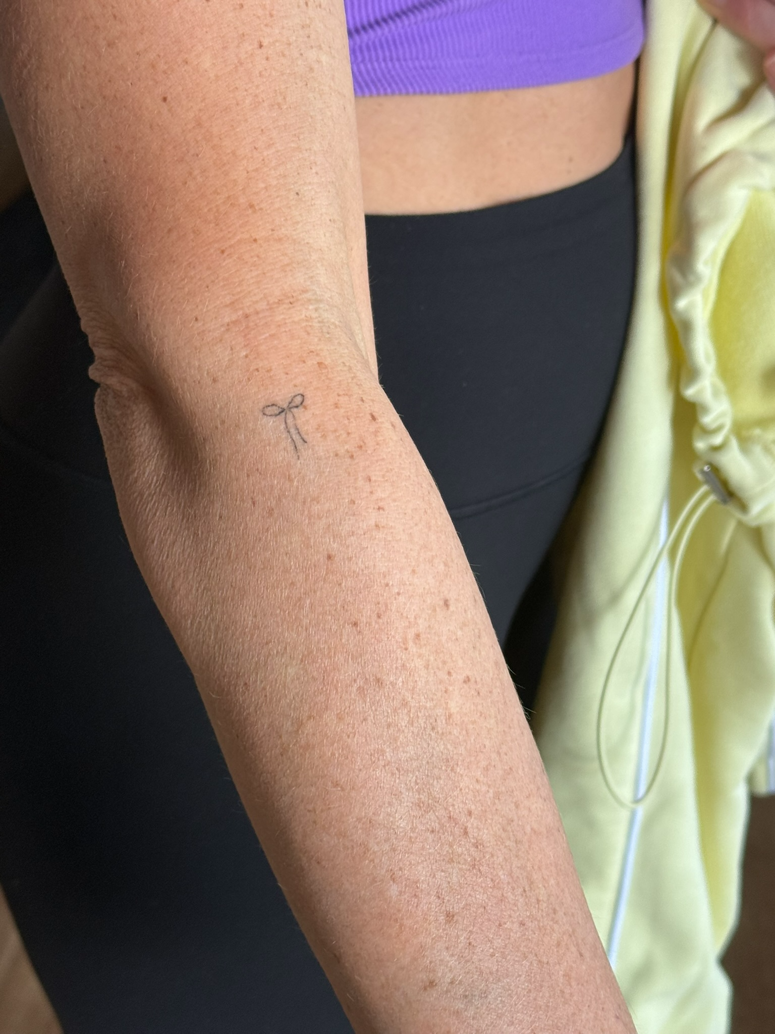 Healed tiny fine line bow tattoo