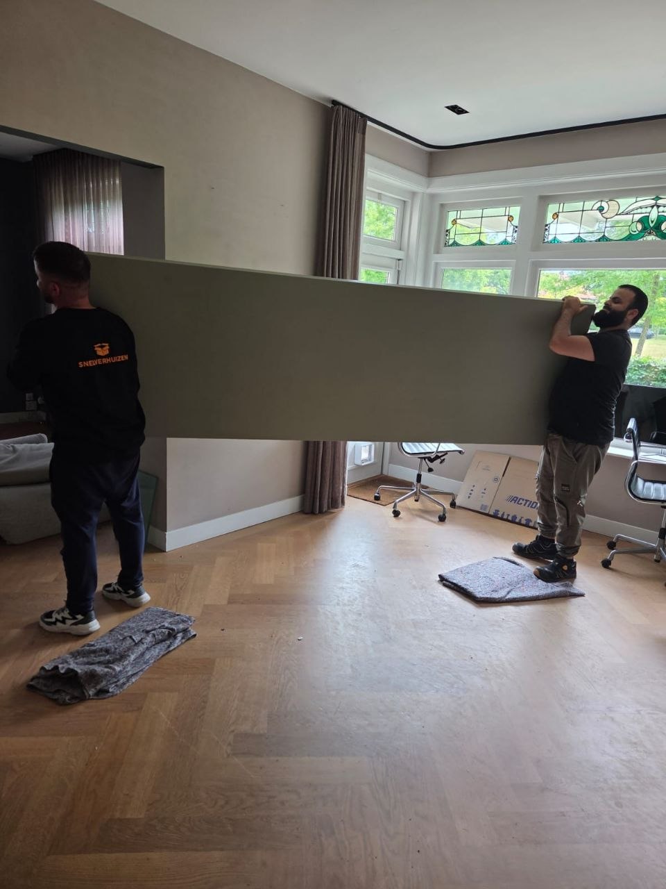 Verhuizers van Snelverhuizen dragen grote inboedel tijdens een woningontruiming