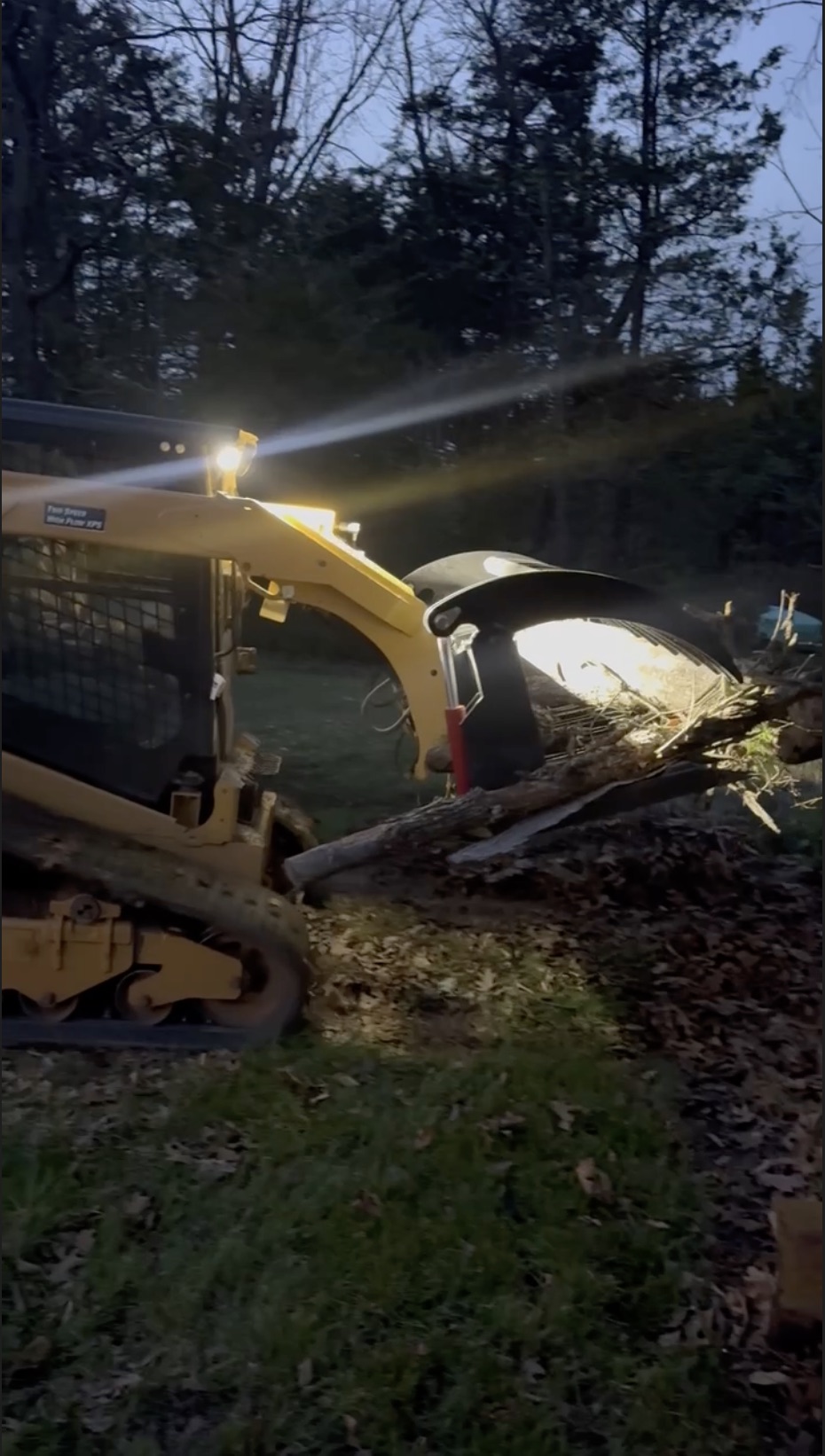 Caterpillar equipment moving logs at dusk