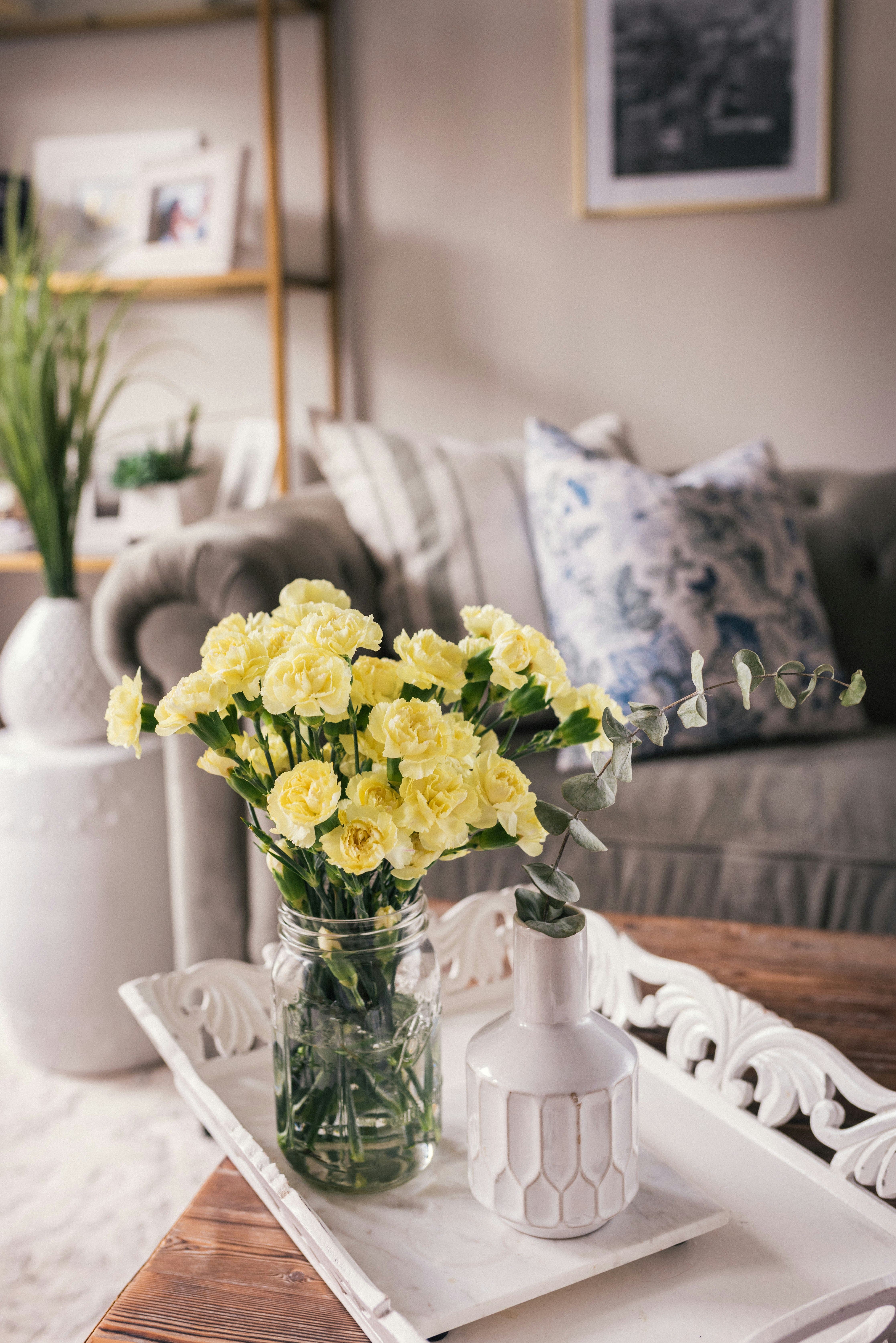 Fresh yellow carnations in a glass jar on a coffee table