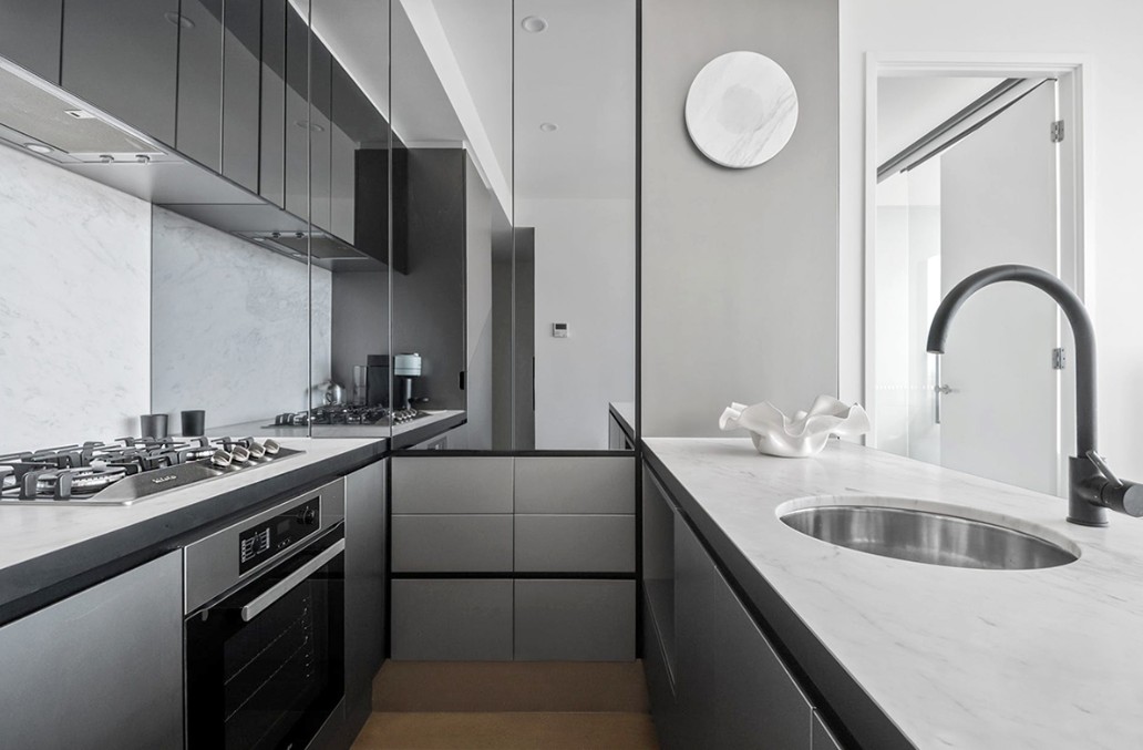 Sleek high-end kitchen with mirrored cabinetry, marble benchtops and matte black tapware