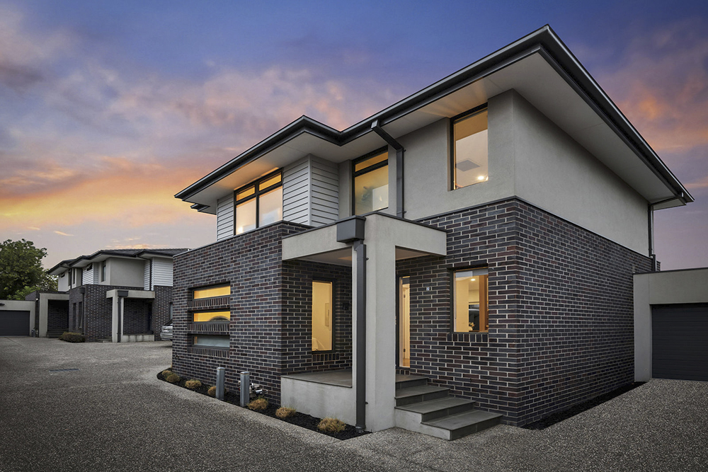 Golden hour real estate photography of a modern brick townhouse with dramatic evening sky