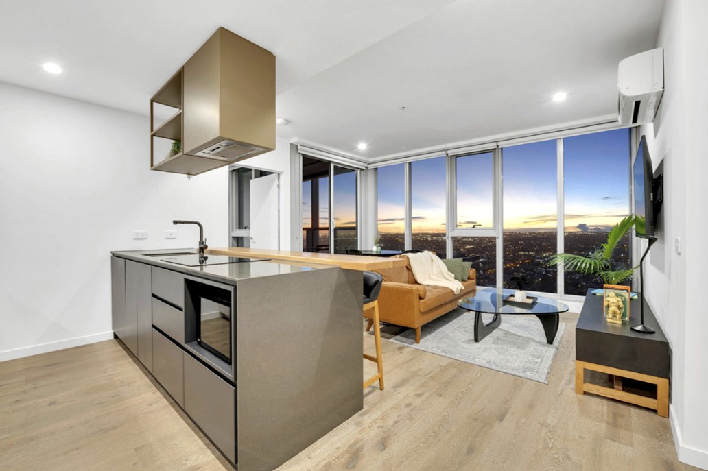 Modern open-plan kitchen and living area with panoramic city skyline views at sunset