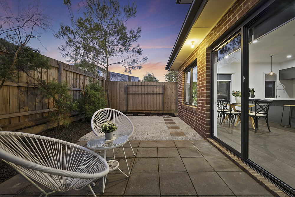 Twilight photography of a modern home courtyard with warm glowing interior lights at dusk