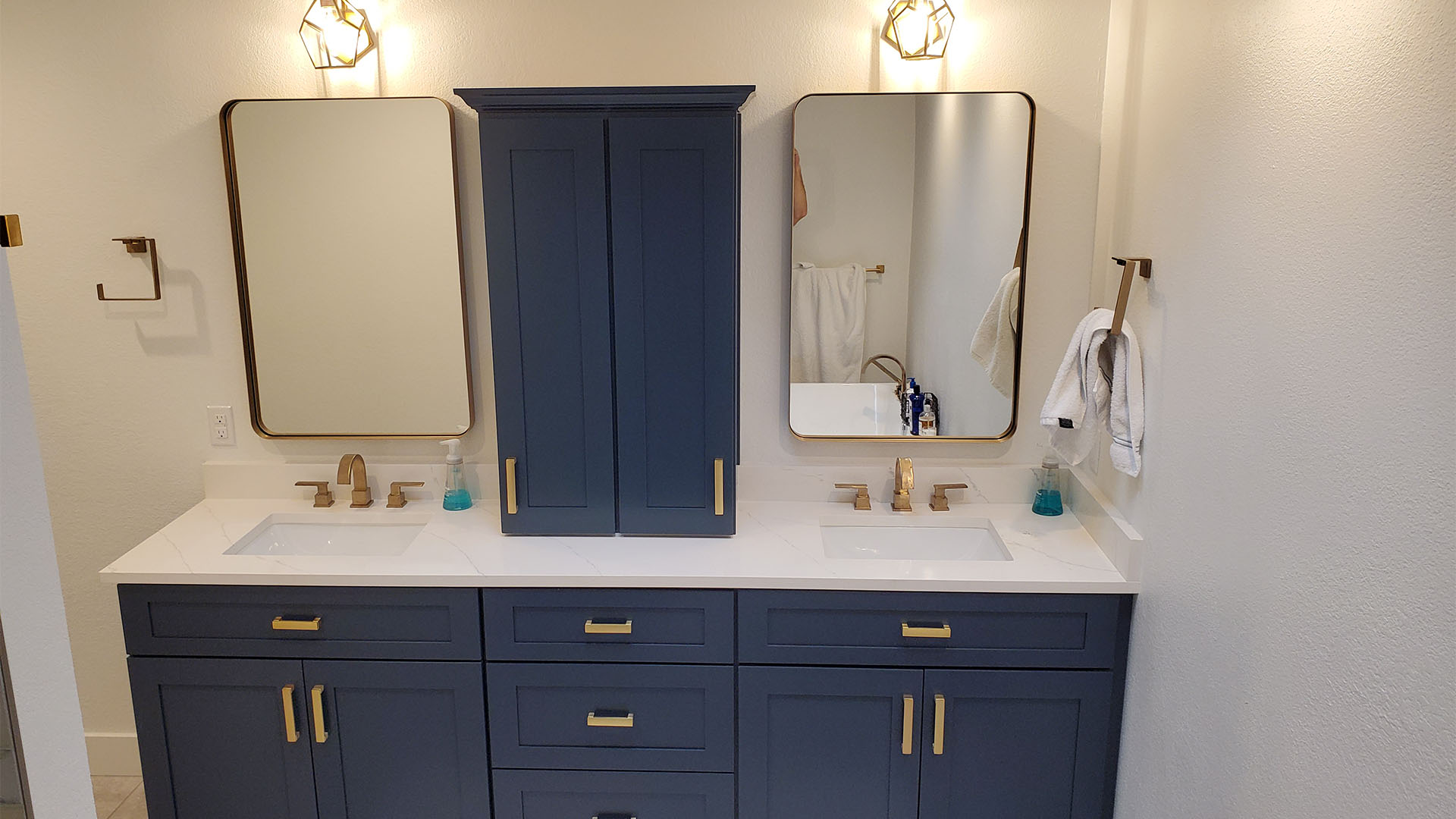 primary bathroom with navy vanity and brass fixtures